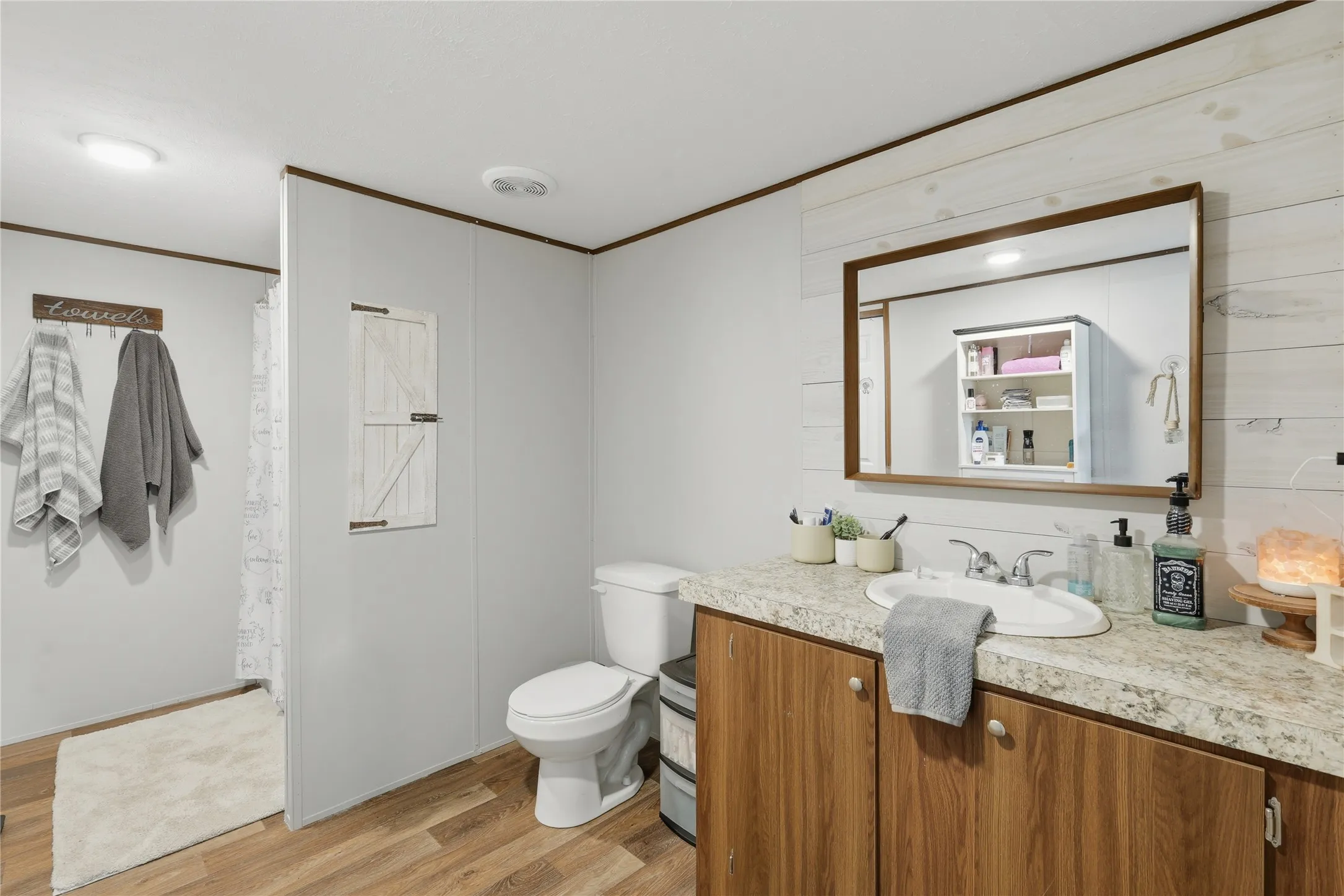 Bathroom vanity featuring a wood-finish cabinet, speckled countertop, and integrated sink