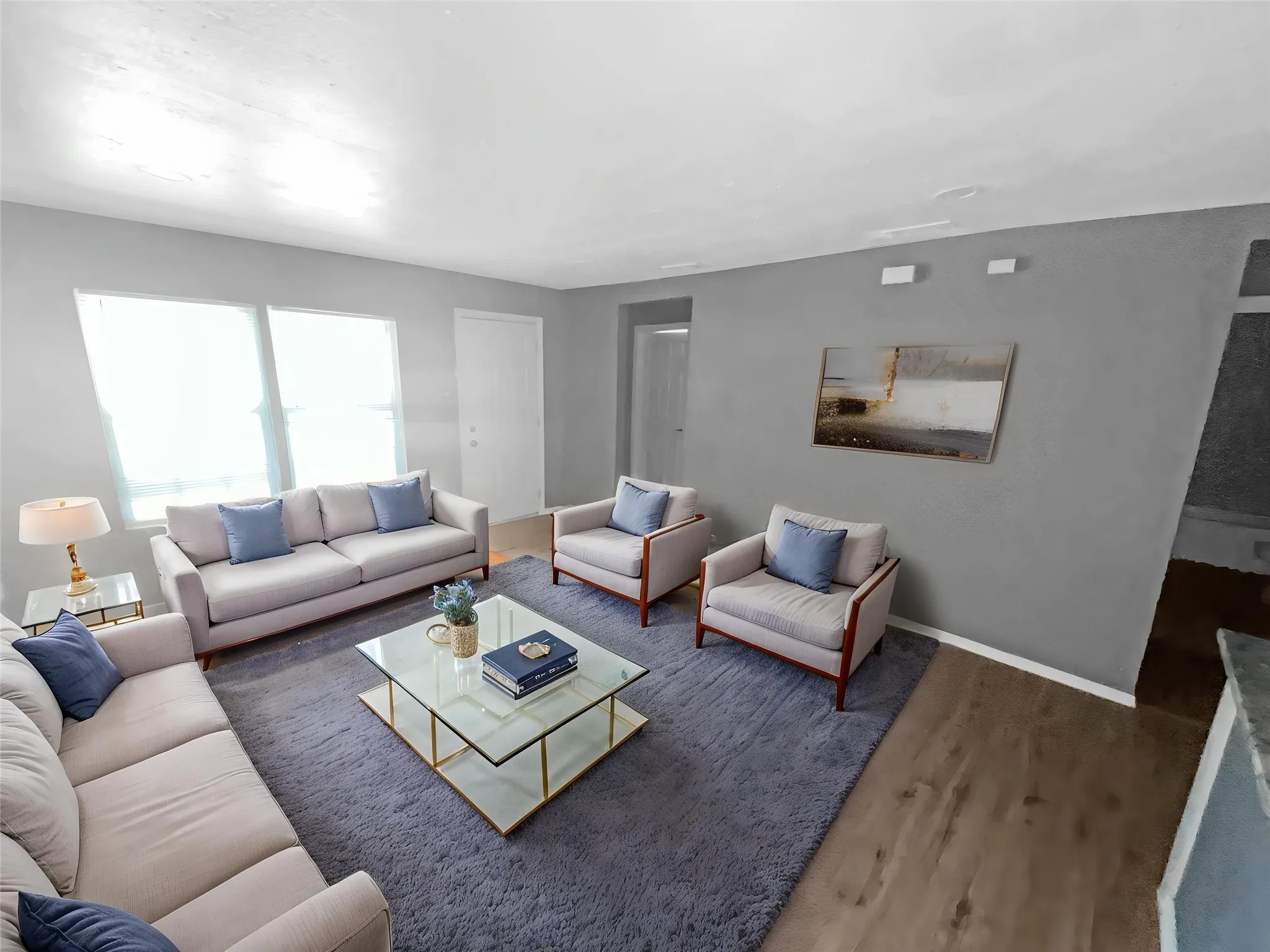 Virtually staged
Spacious living area featuring light gray walls, multiple windows providing ambient light, wood-finish flooring, and a ceiling-mounted light fixture