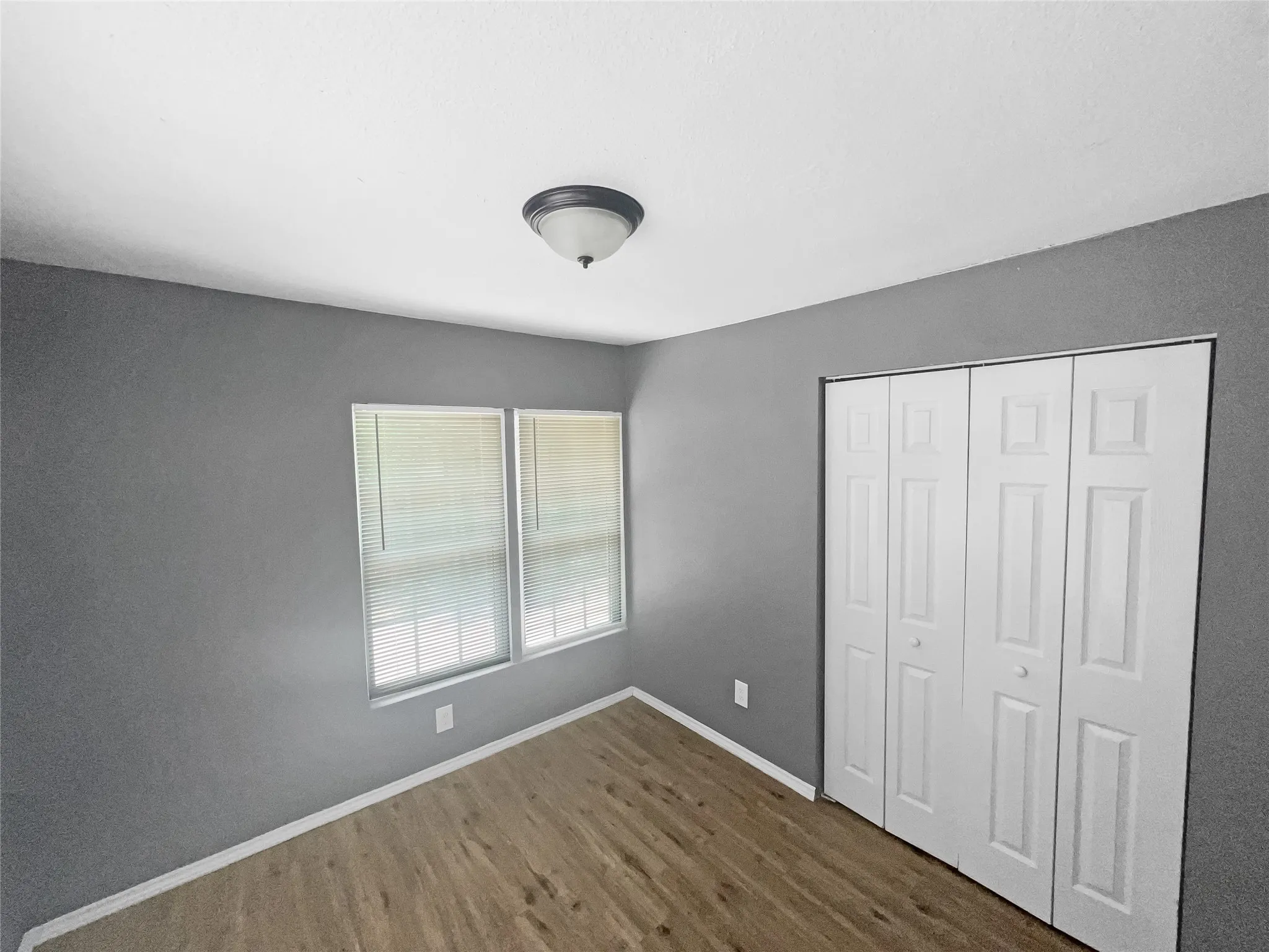 Room featuring wood-finish flooring, neutral gray wall tones, and white trim