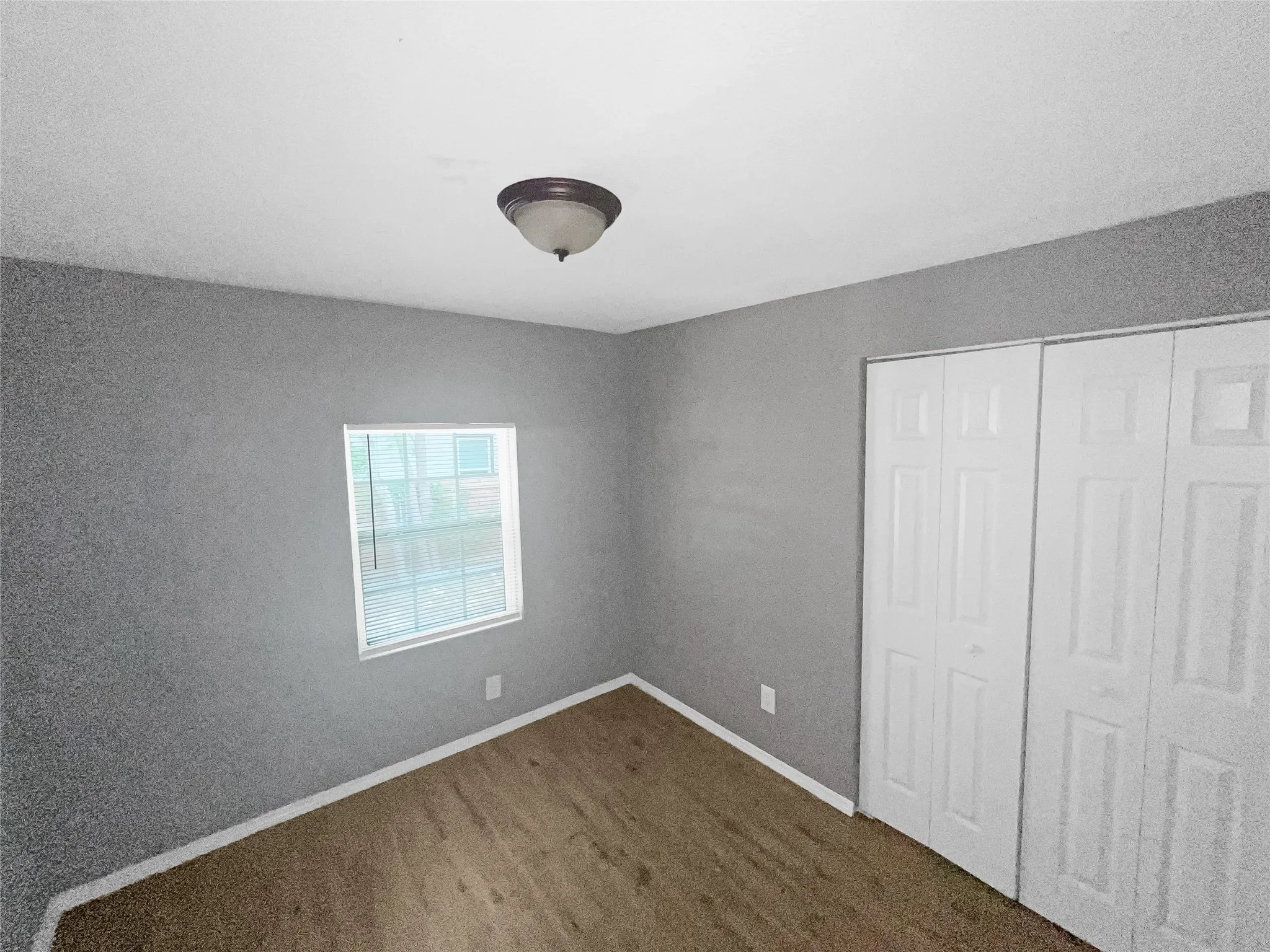 Room featuring light gray walls, a single window with white trim, and a ceiling-mounted light fixture