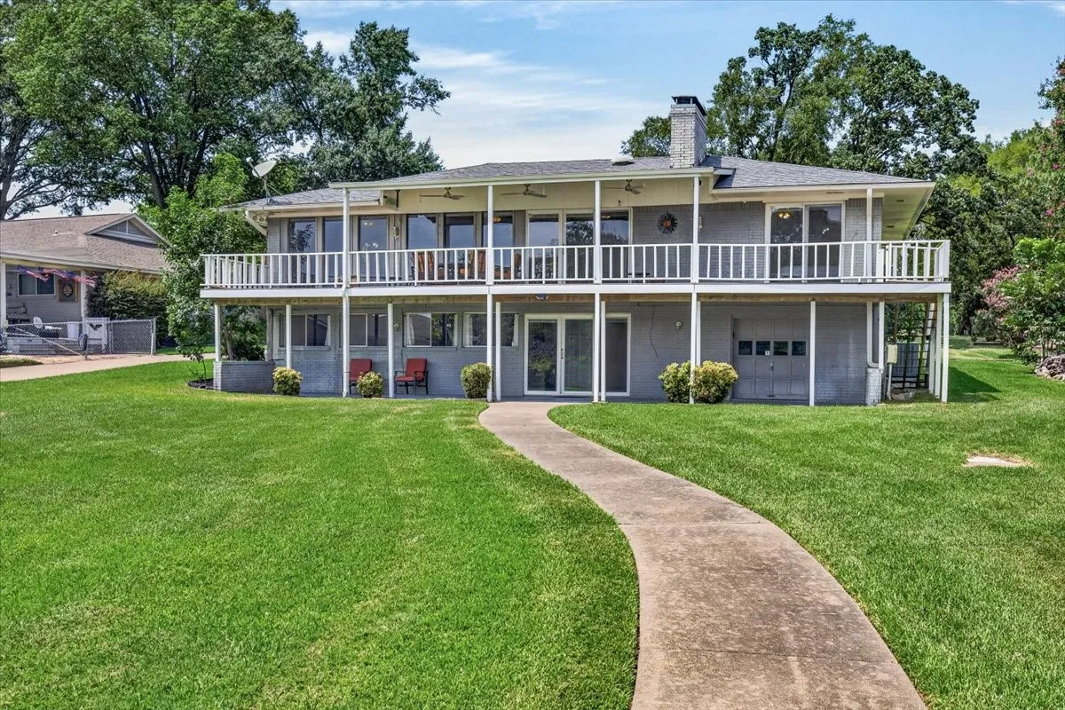 Back elevation from lake showing upper main level of lower level of home.  Beautiful and spacious covered porch decks and expansive lush lakeside yard for endless possibilities for lake side entertaining.