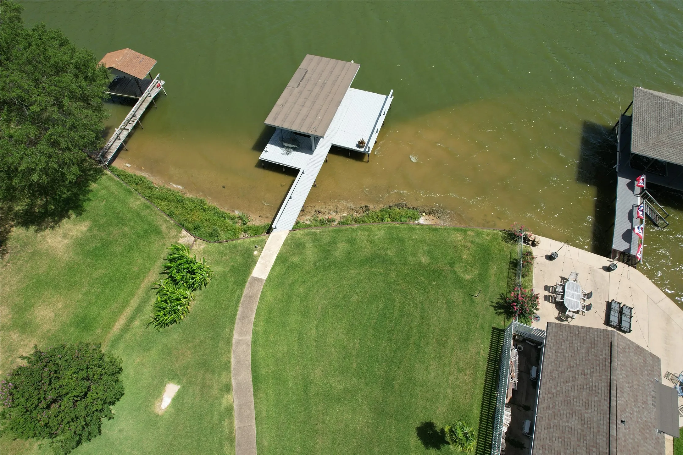 160 Santa Monica featuring a covered boat dock, a paved walkway to the water, and a large grass lawn