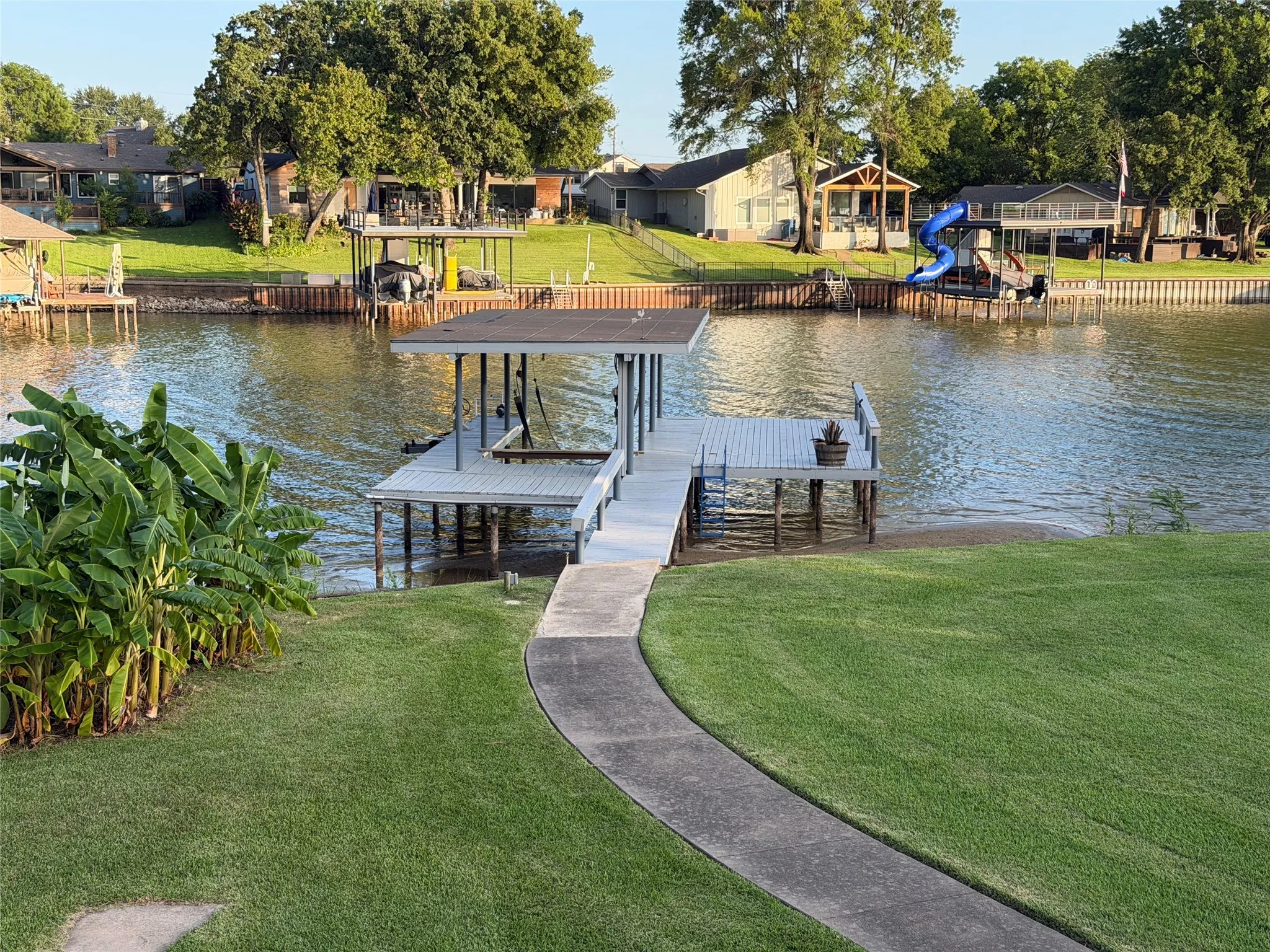 Concrete pathway from house leading to boat dock with covered slip and open deck