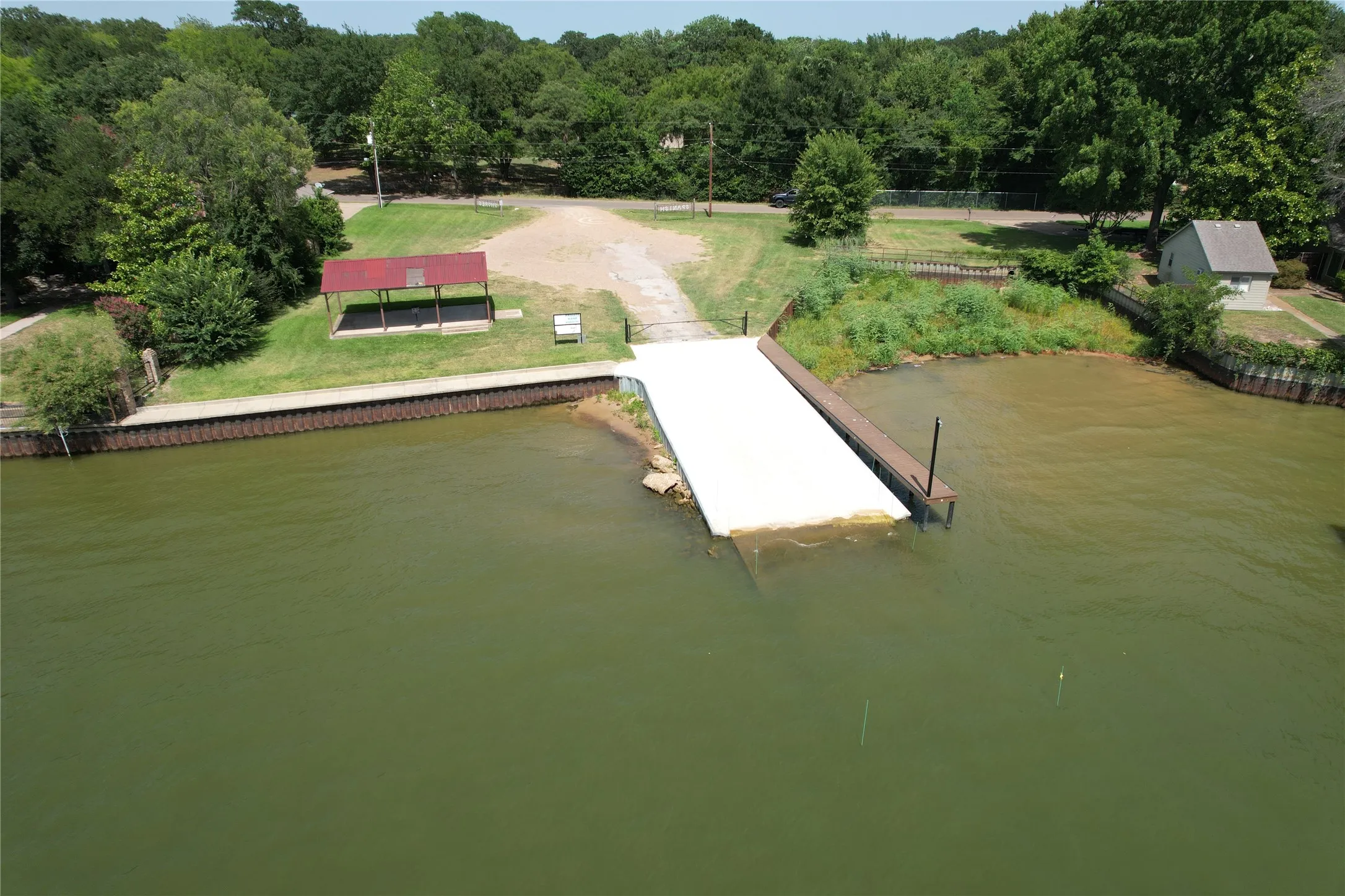 Spanish Shores Park view from the lake featuring a boat ramp, fishing pier, covered picnic pavillion and expansive lawn area.