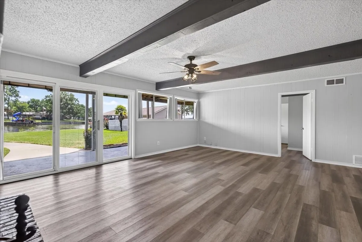 Downstairs walk-out basement game room living area featuring wood-finish flooring, direct outdoor access via sliding glass doors to the lake side yard.  Downstairs also has a large cedar lined storage closet, bedroom with ensuite bathroom and walk-in closet (through open door in photo)