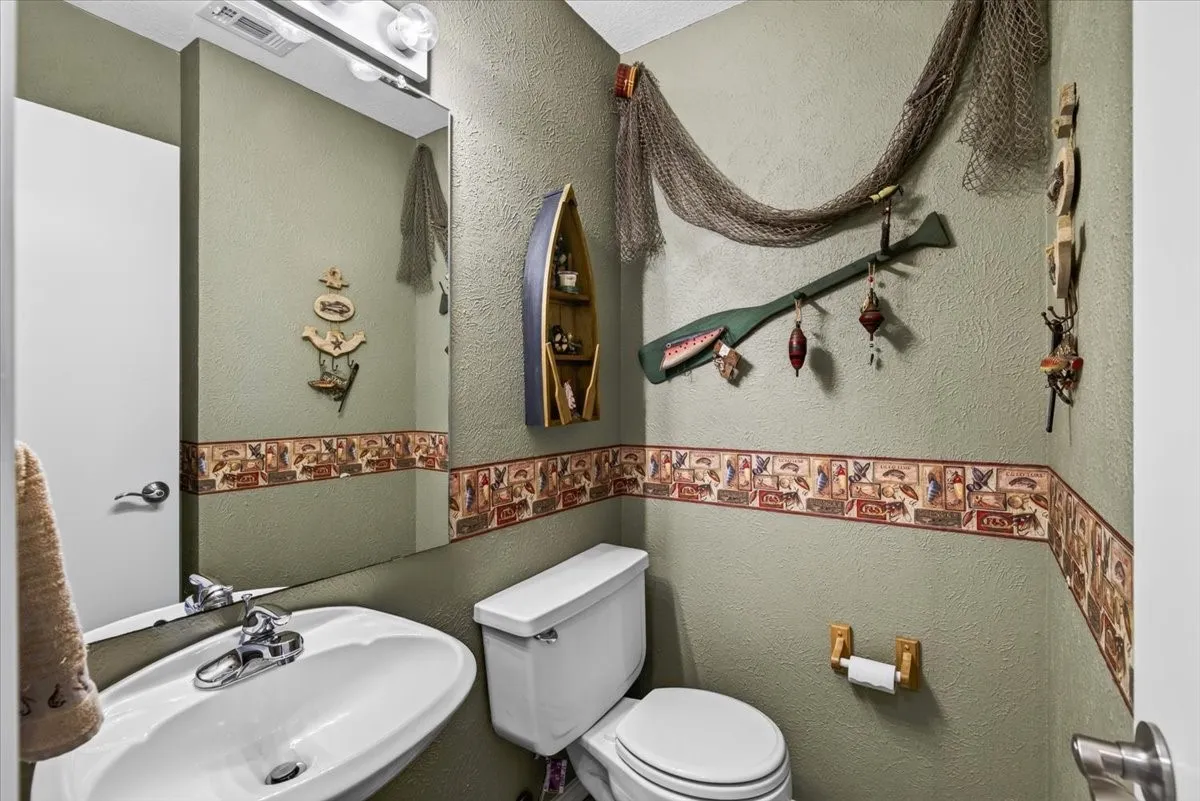 Main level half-bath with Pedestal sink, wall-mounted mirror, and overhead vanity lighting