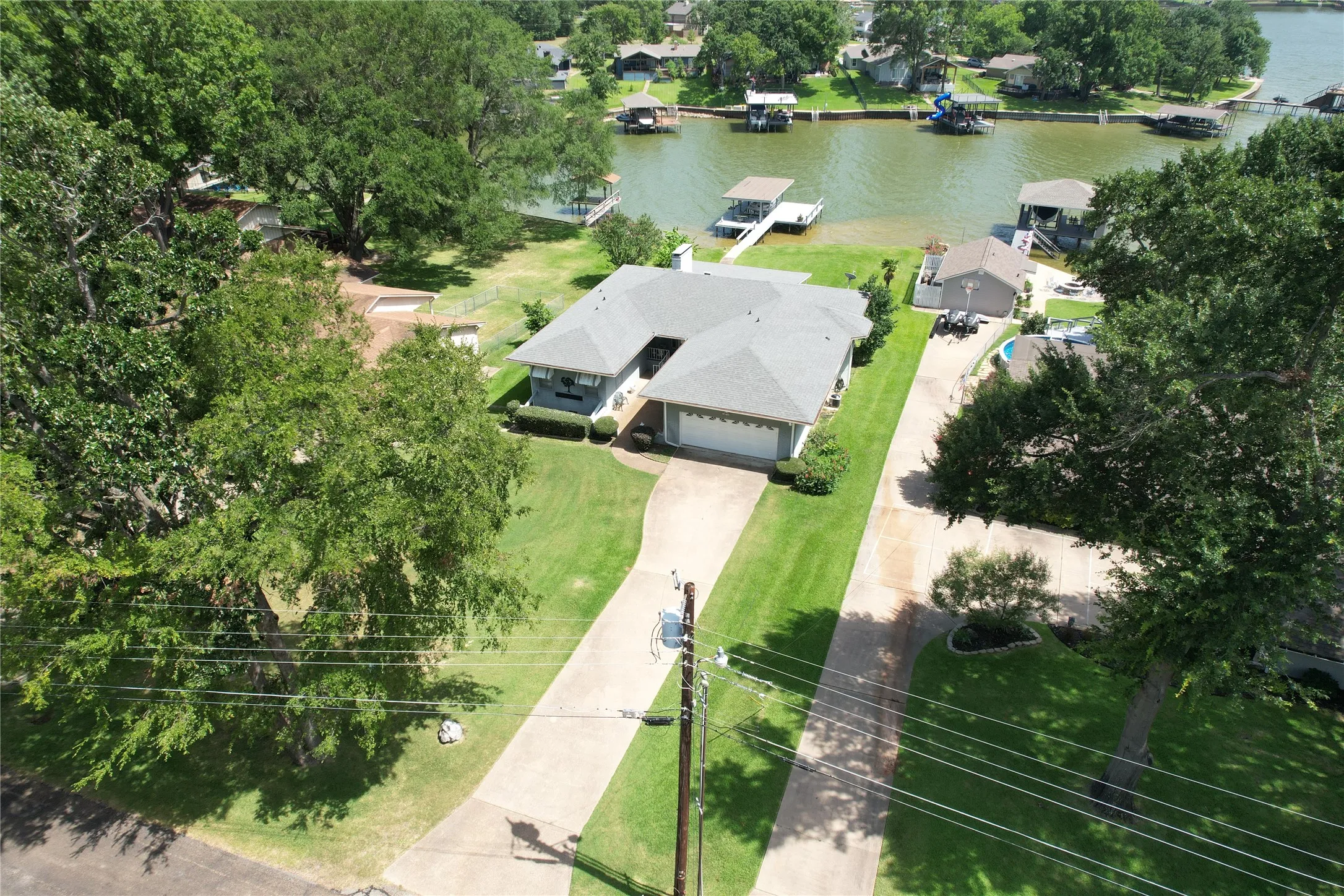 Water front Single-story ranch-style residence featuring a gray shingle roof, attached garage, and a concrete driveway