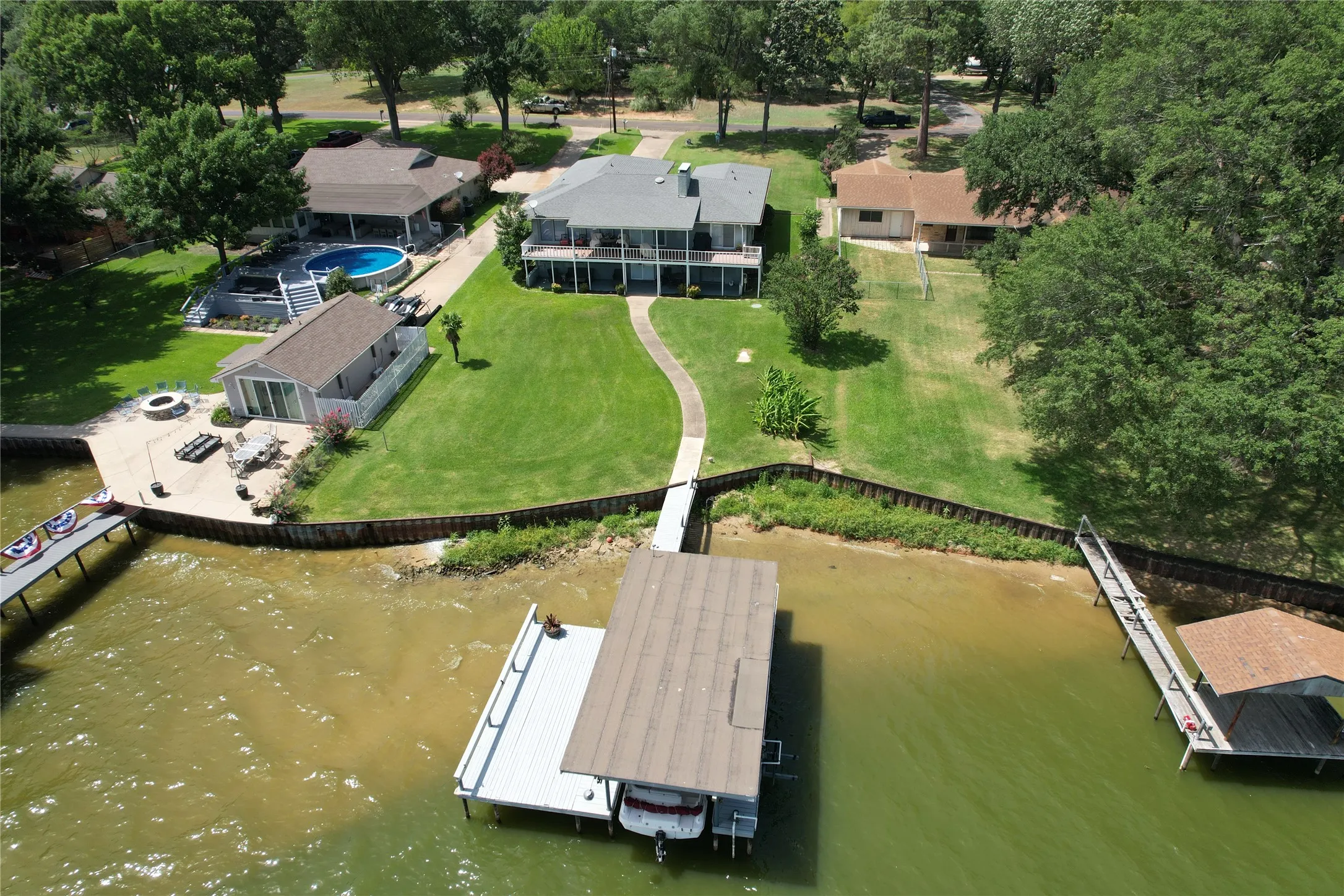 Waterfront 3/2.5/2.5 home with private boat dock featuring a covered slip, expansive manicured lawn, and a water depth most boaters will love :-) - note the dark green water under boat house. Photo taken June 29, 2026.