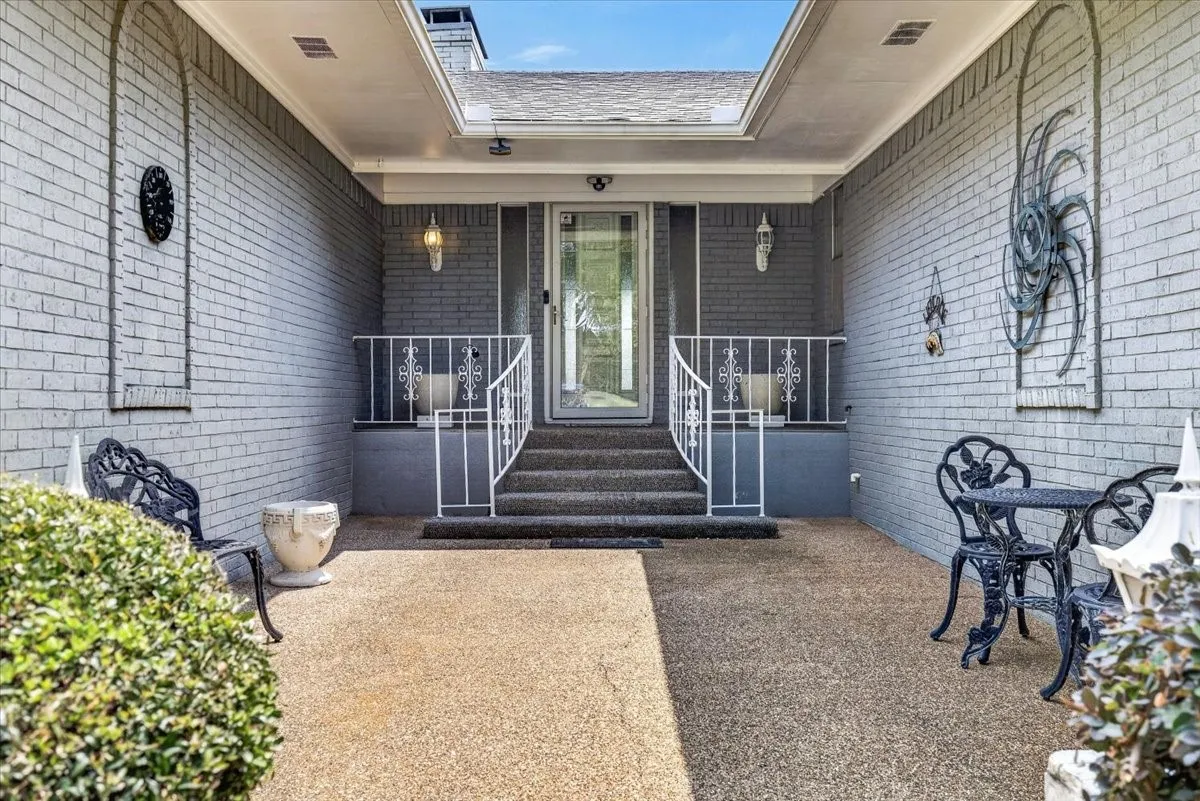 Front entry courtyard brick exterior with arched wall accents, covered entry, and exposed aggregate patio
