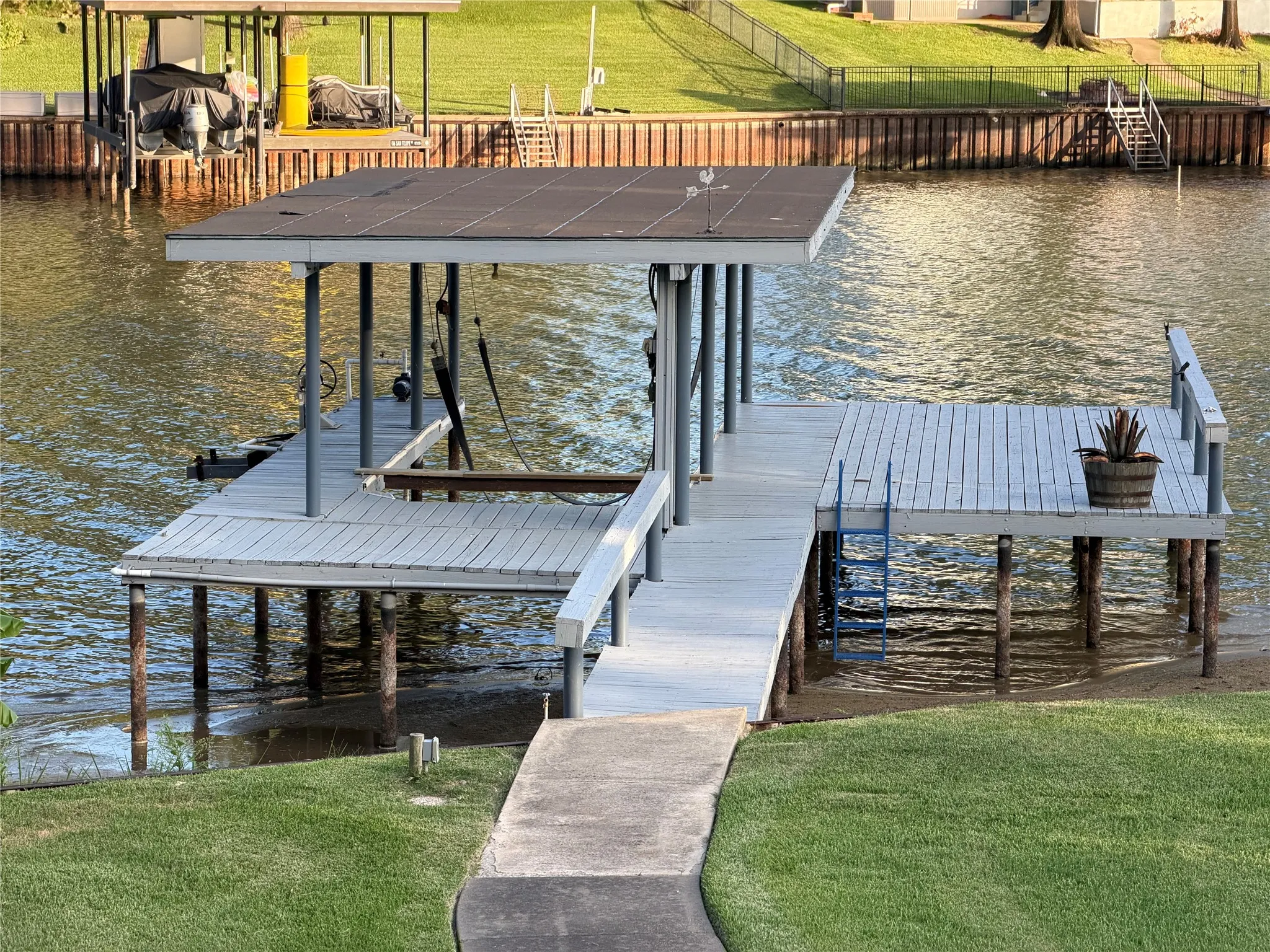 Waterfront boat dock, photo taken when lake was 3.86' low (TWRD) and featuring a covered slip, boat lift straps, personal water craft lift, a spacious open deck area, and a pier for access
