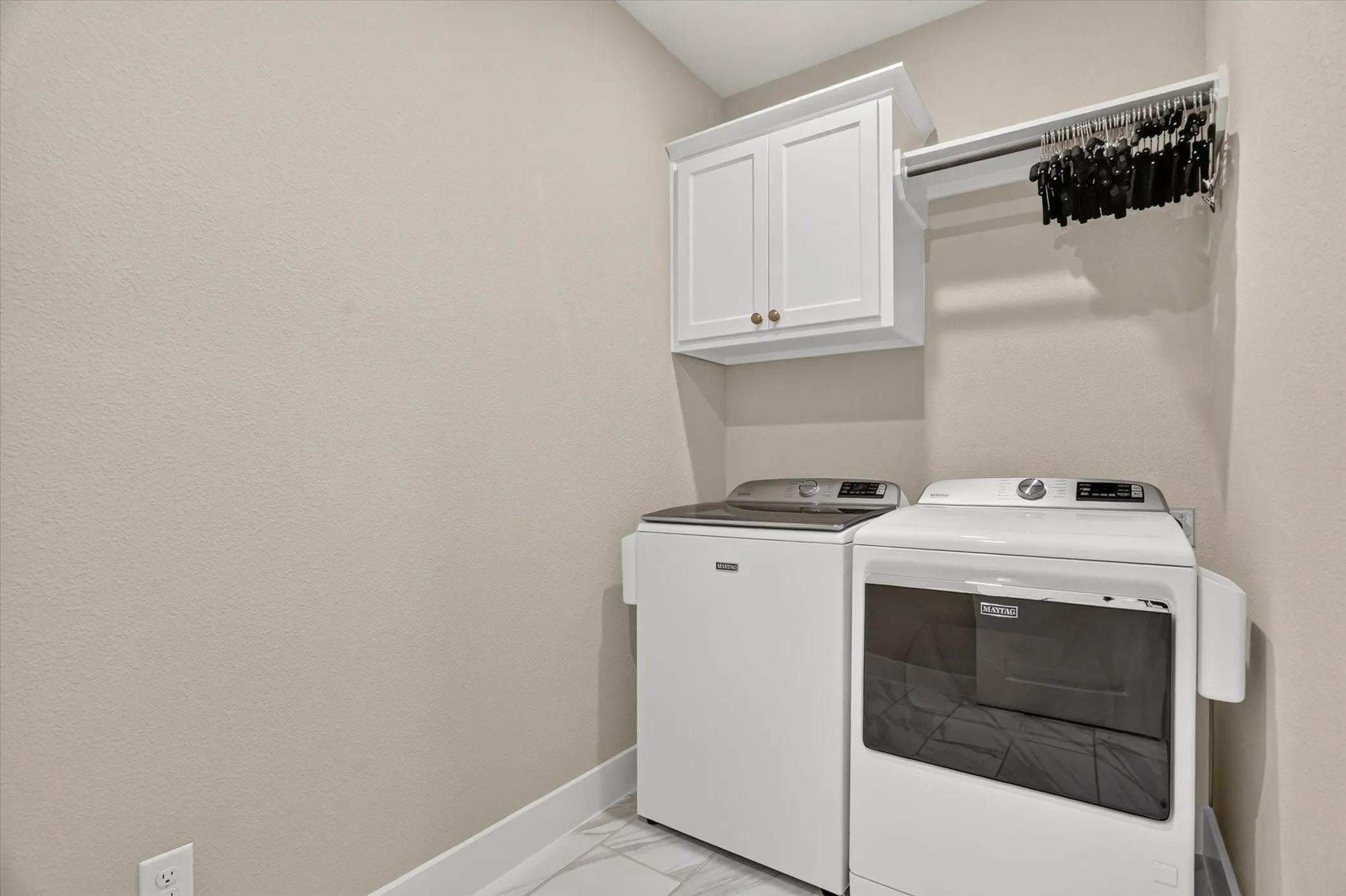 Dedicated laundry area featuring white wall cabinetry, a hanging rod, and a neutral wall finish