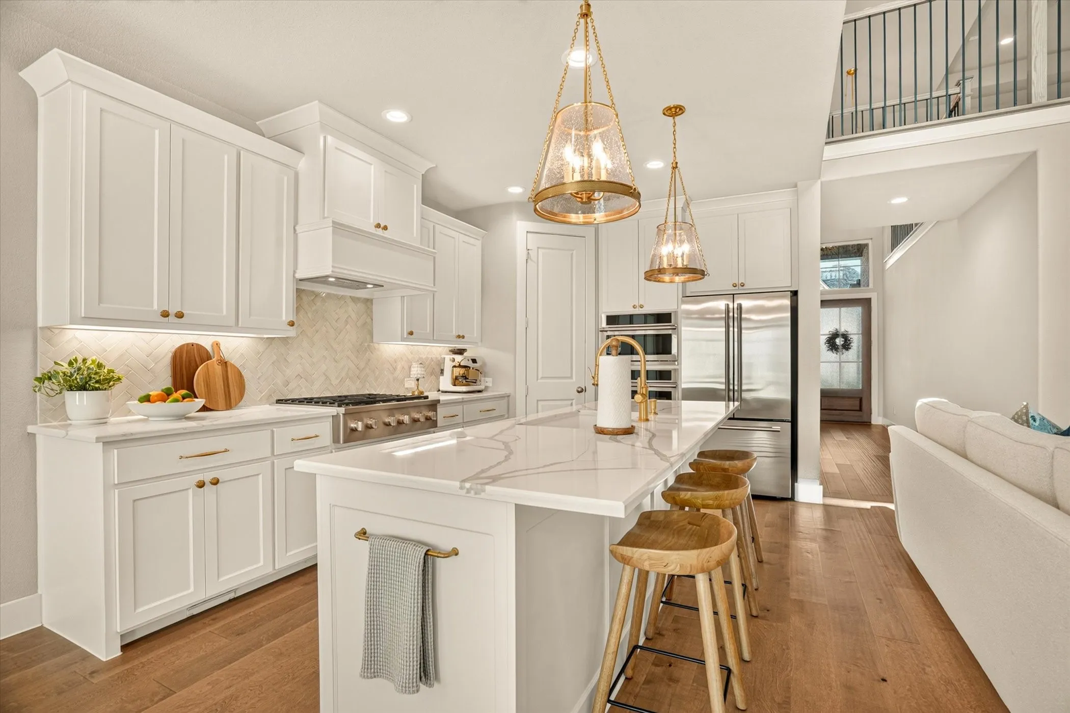 Expansive kitchen featuring a large central island with seating, a high-end range, stainless steel appliances, white cabinetry, and wood-finish flooring