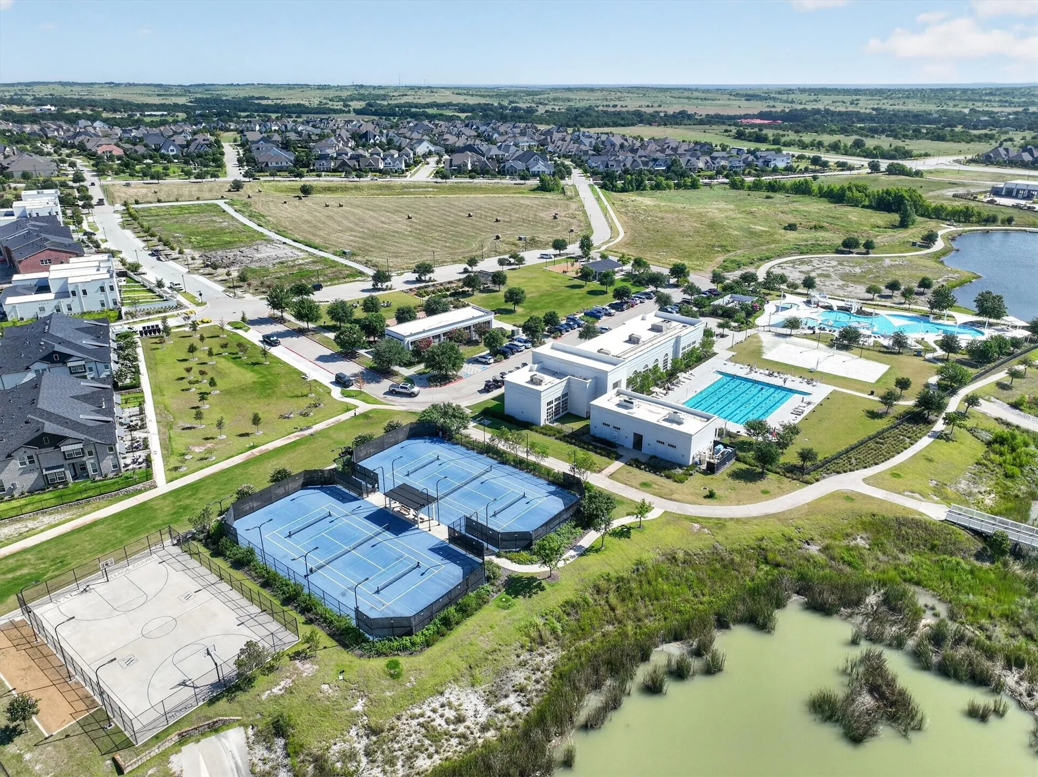 Aerial perspective showcasing community amenities including multiple tennis courts, a basketball court, and two swimming pools