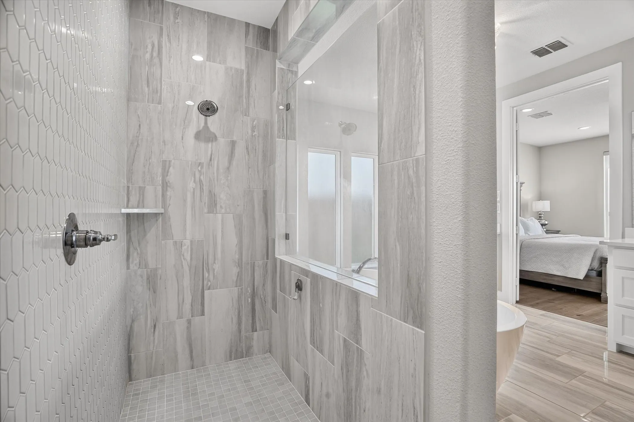 Spacious shower featuring floor-to-ceiling tile, a built-in shelf, and a rainfall showerhead