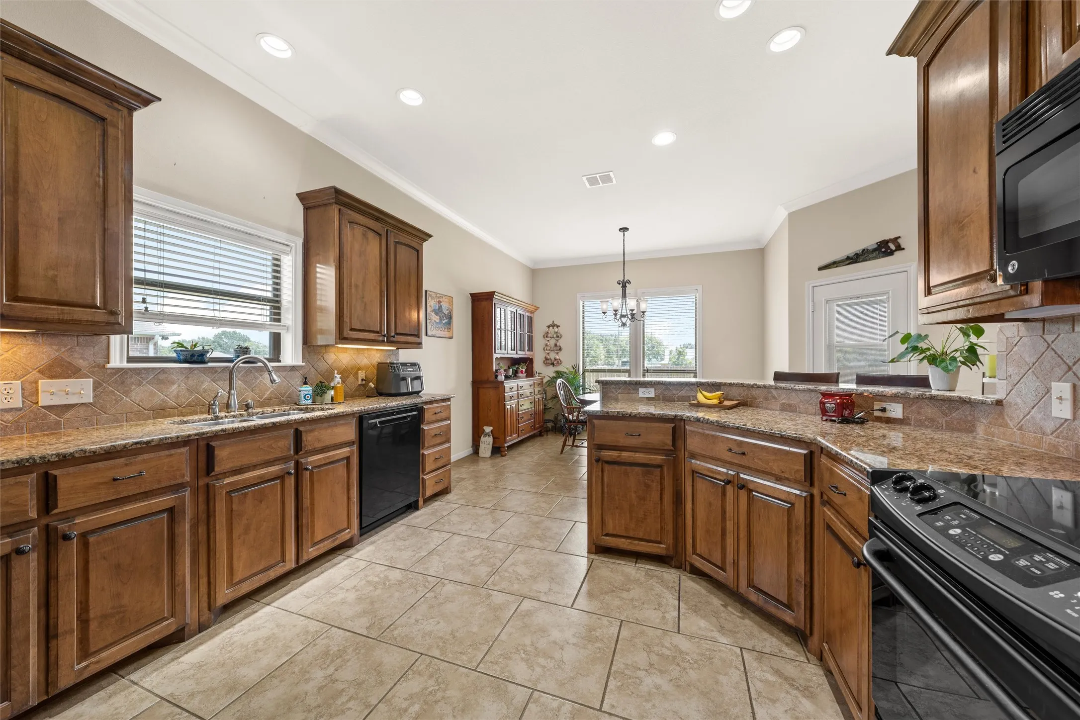 Spacious kitchen featuring warm wood cabinetry, granite-finish countertops, and a full tile backsplash