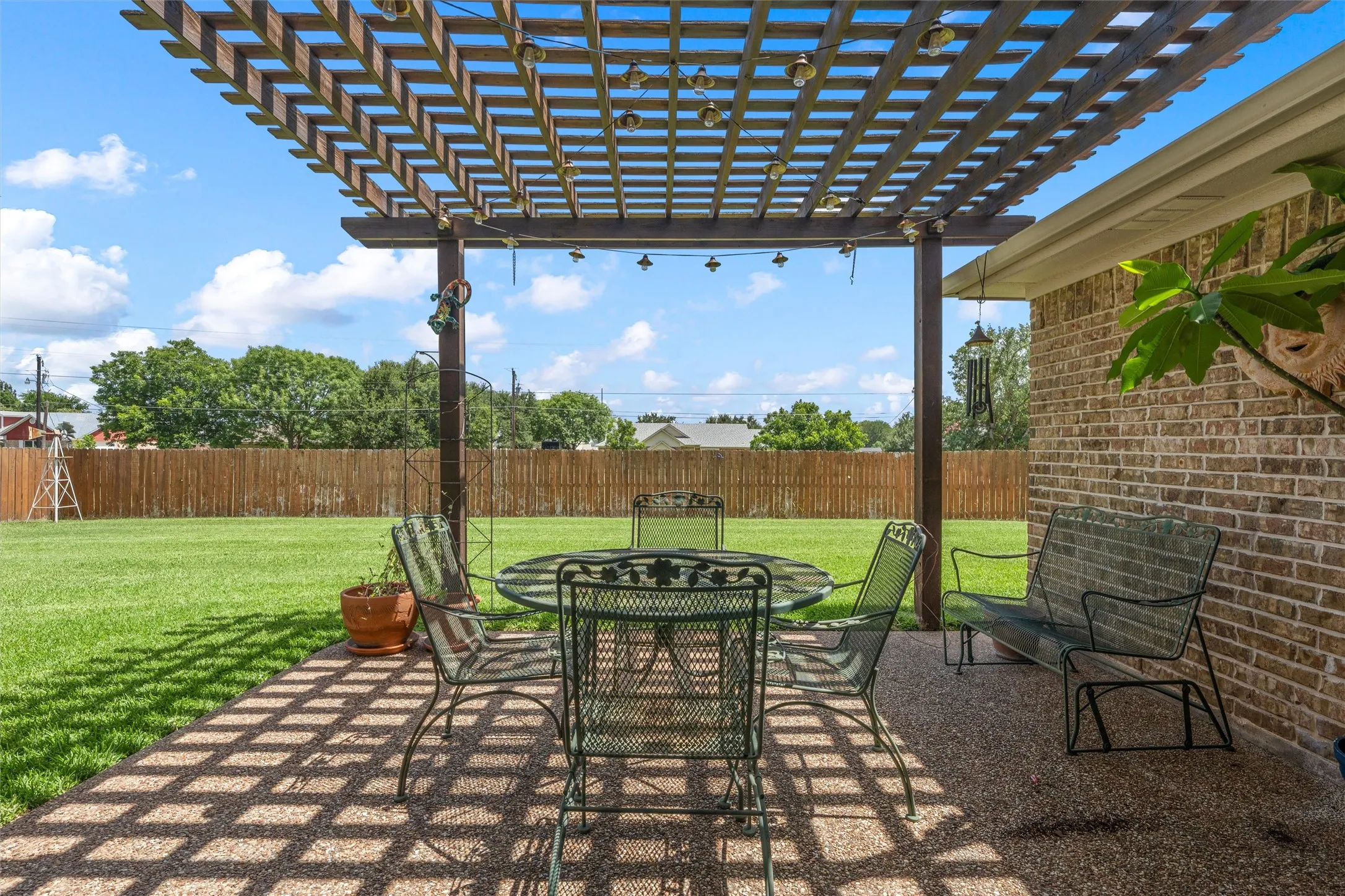 Expansive backyard featuring a wood pergola and a gravel patio