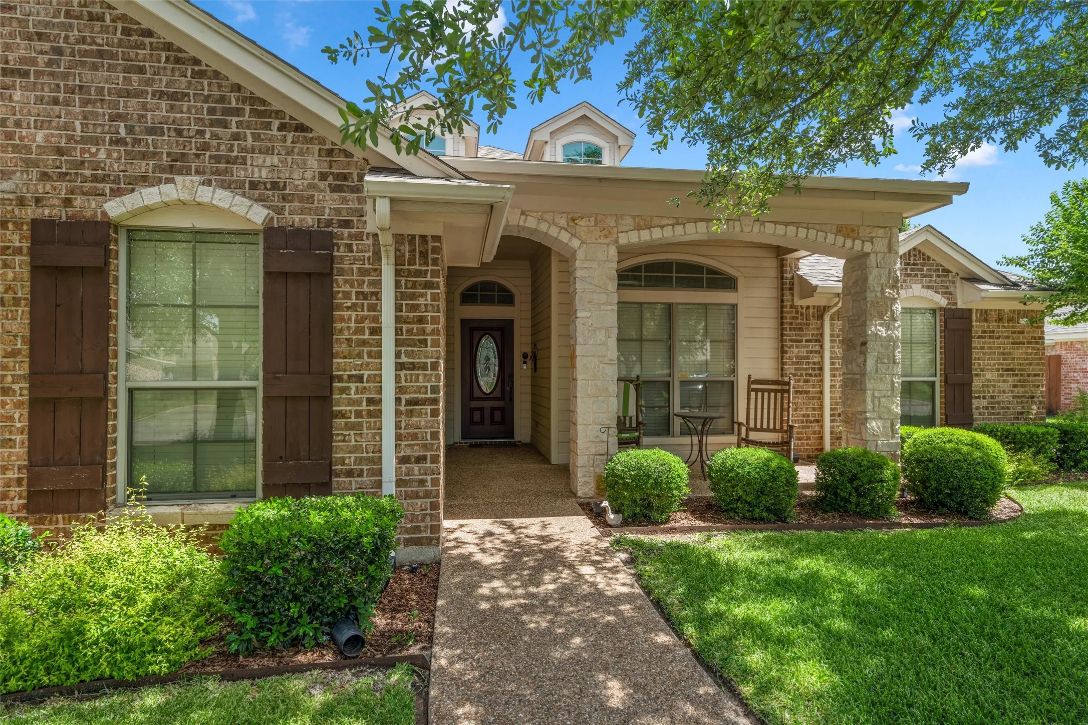 Brick and stone exterior featuring a covered porch with stone columns