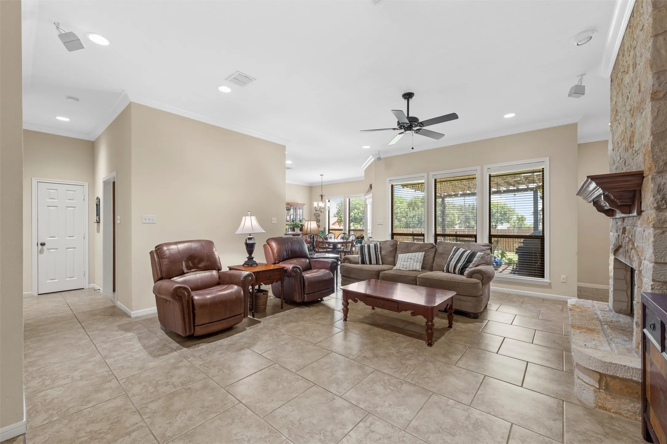 Spacious living area featuring neutral-toned tile flooring, recessed lighting, and crown molding