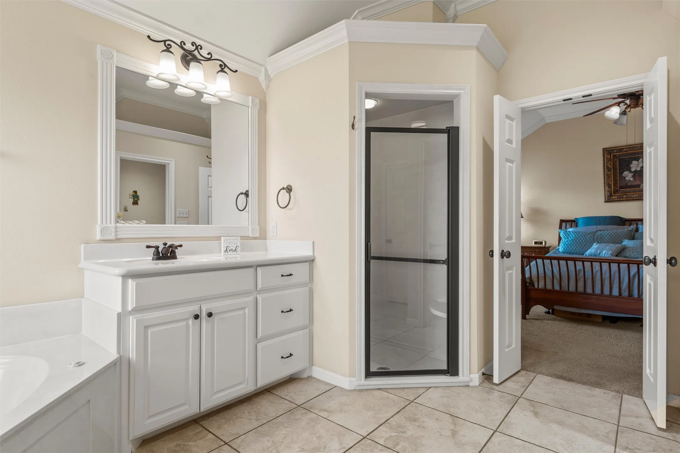 Bathroom featuring a white vanity with integrated sink, framed mirror, and a shower enclosure with a dark frame