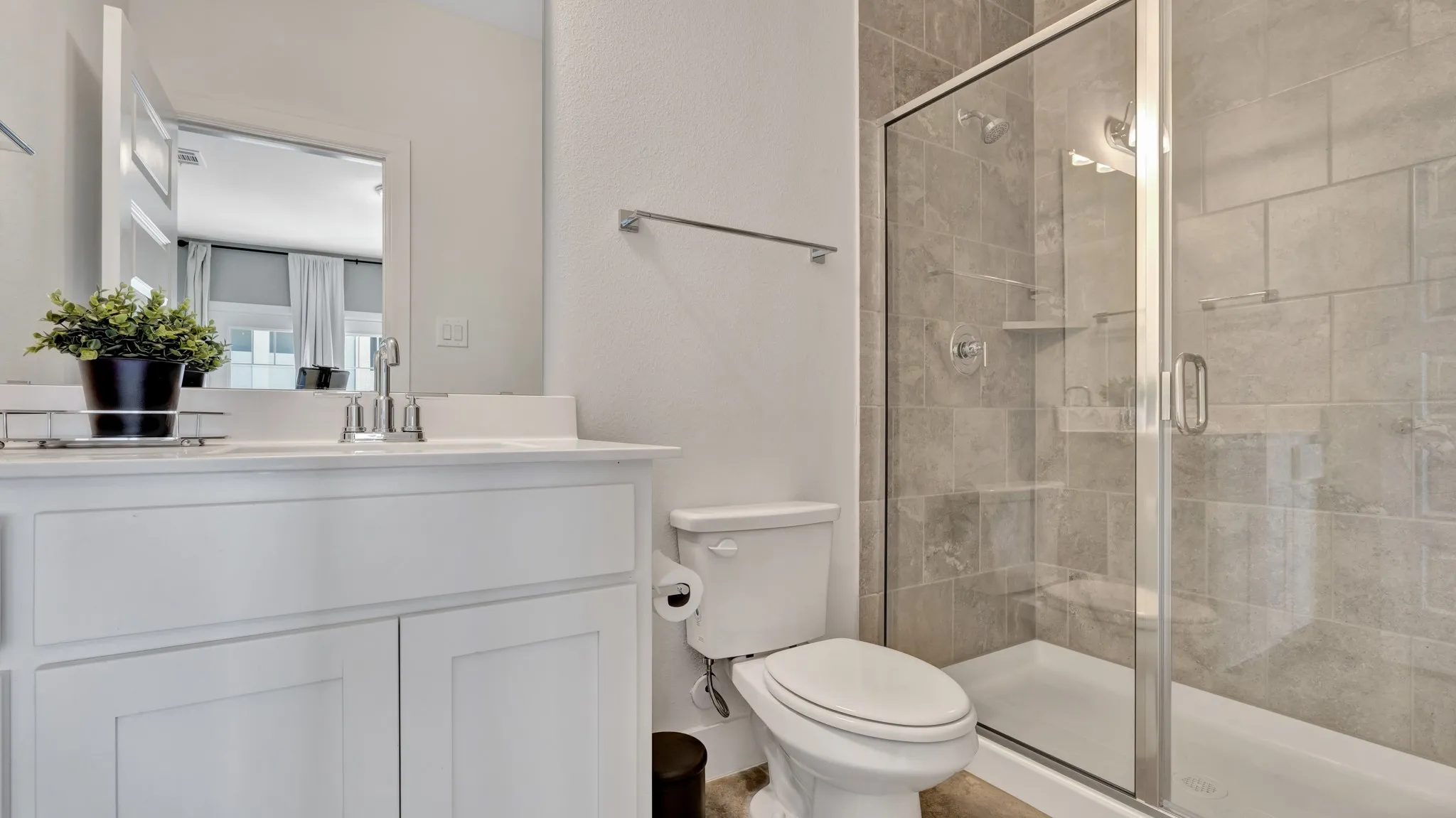 Secondary bedroom, ensuite, featuring a glass-enclosed shower with tile surround, white vanity with integrated sink, and contemporary fixtures