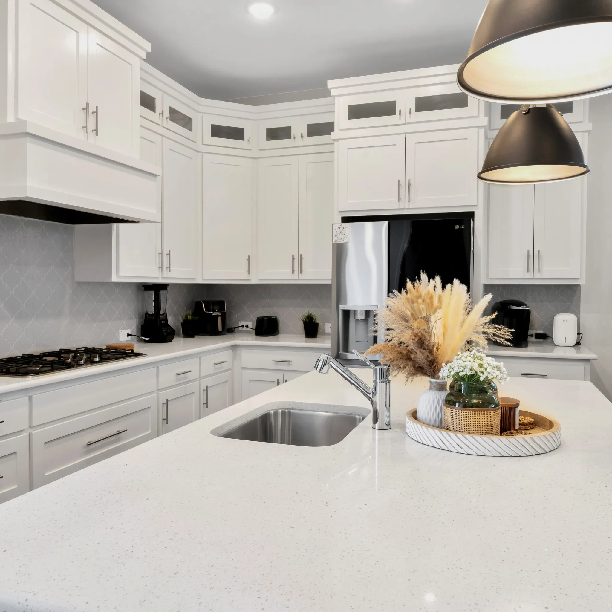 Modern kitchen featuring white cabinetry, a large center island with an undermount sink, a gas cooktop, and stainless steel appliances.