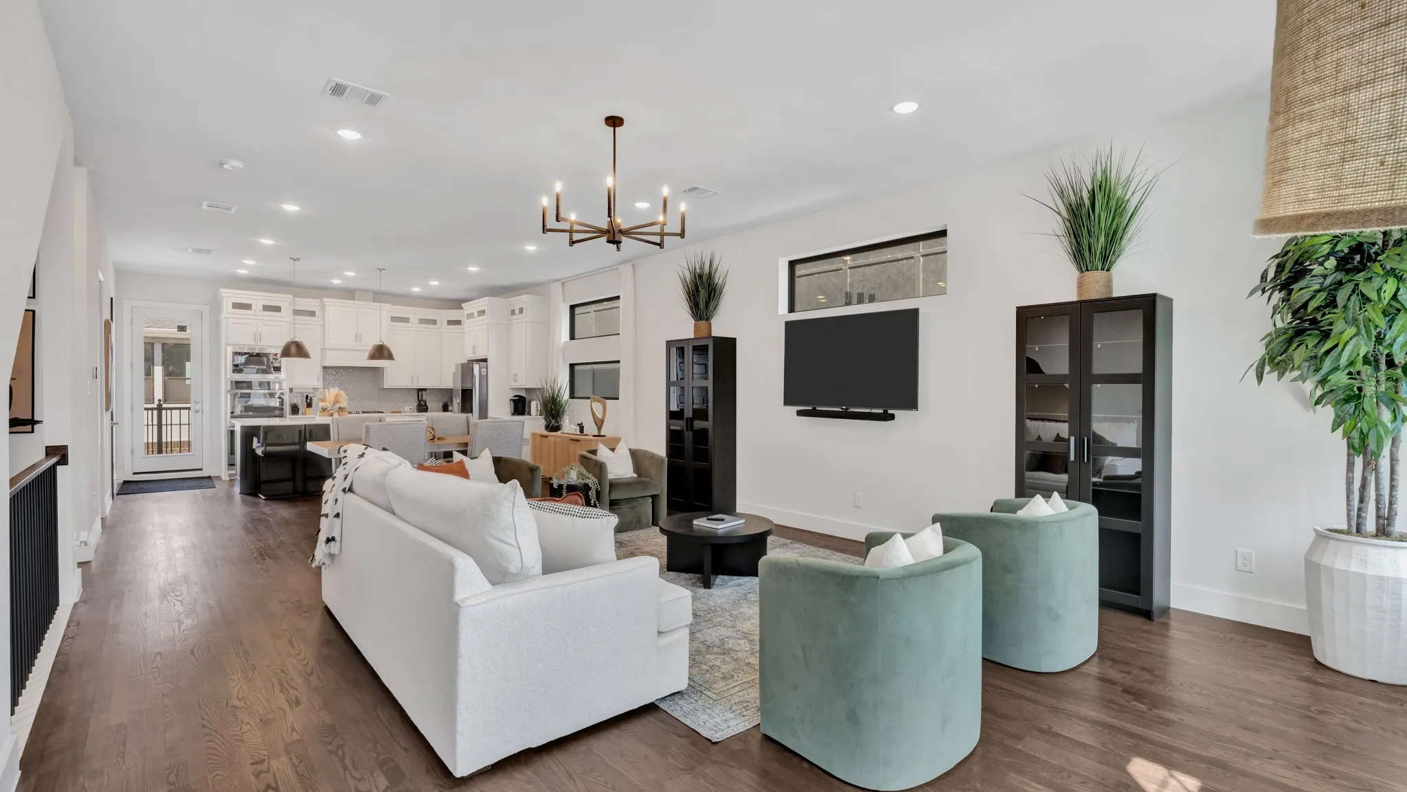 Open-concept living space featuring wood-finish flooring, recessed lighting, and a modern chandelier