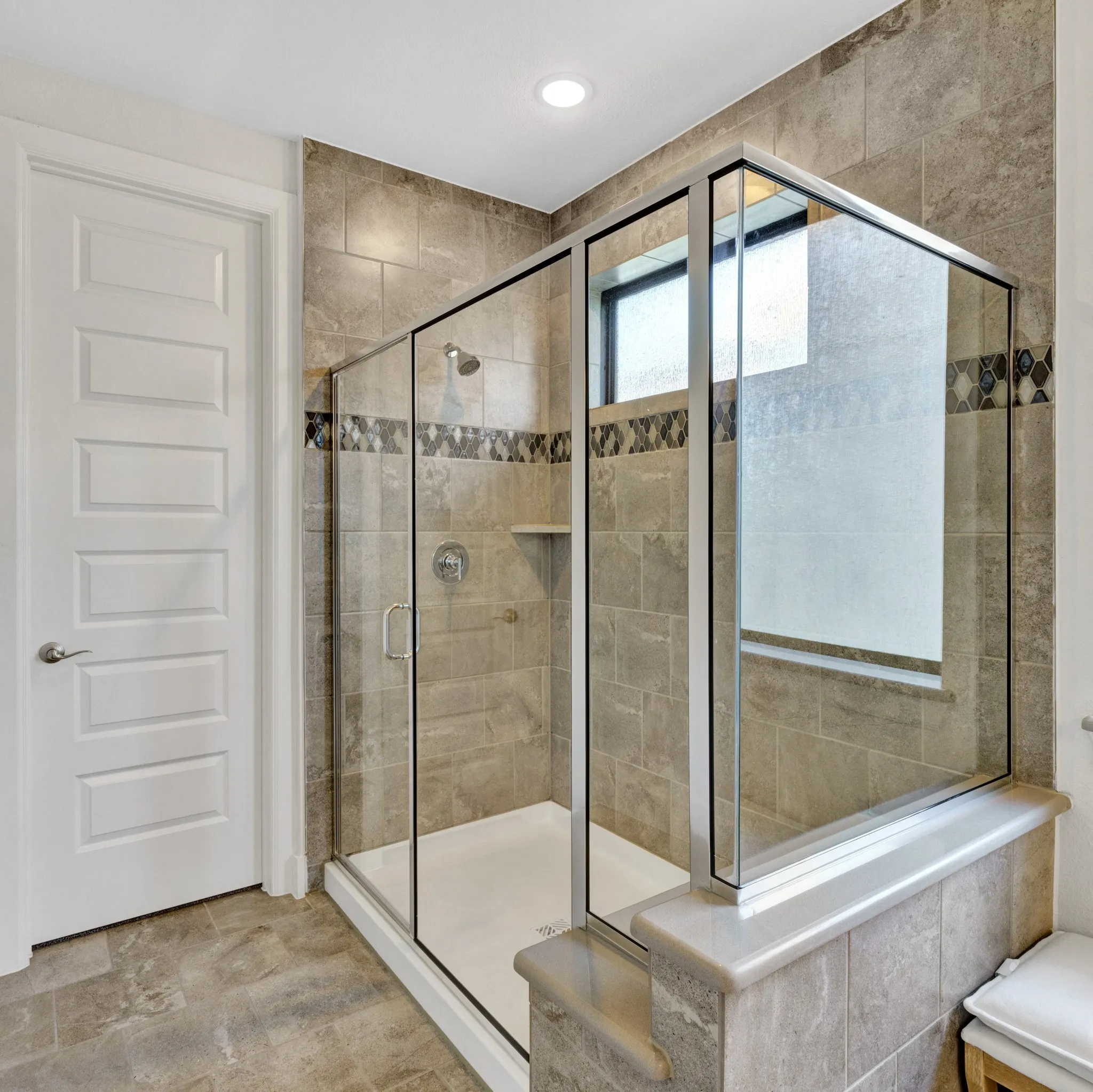 Master bathroom, ensuite featuring a glass-enclosed shower with full tile surround, integrated shower niche, and mosaic tile accent band