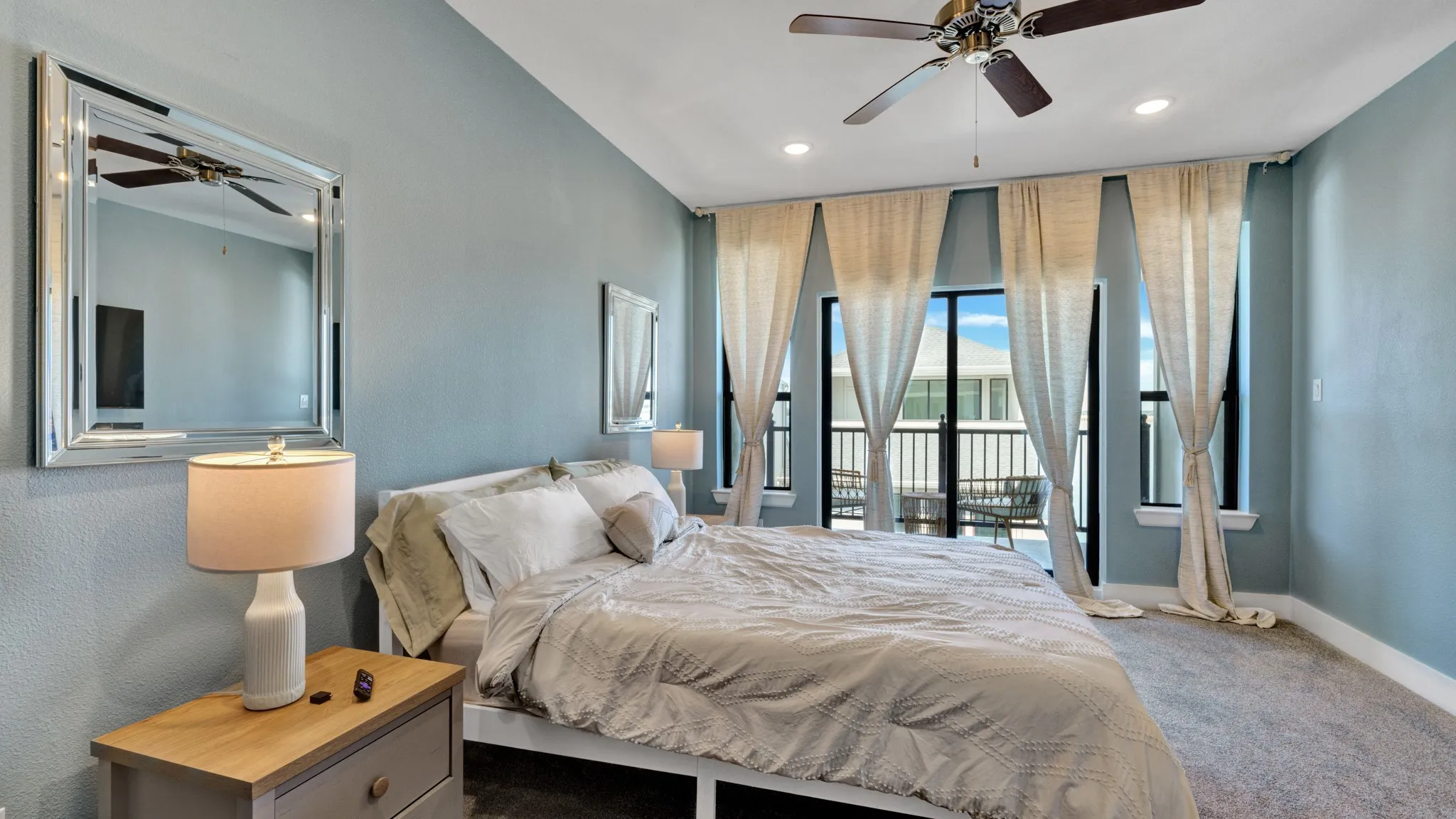 Bedroom featuring a private balcony with black railings, four large windows, and recessed lighting