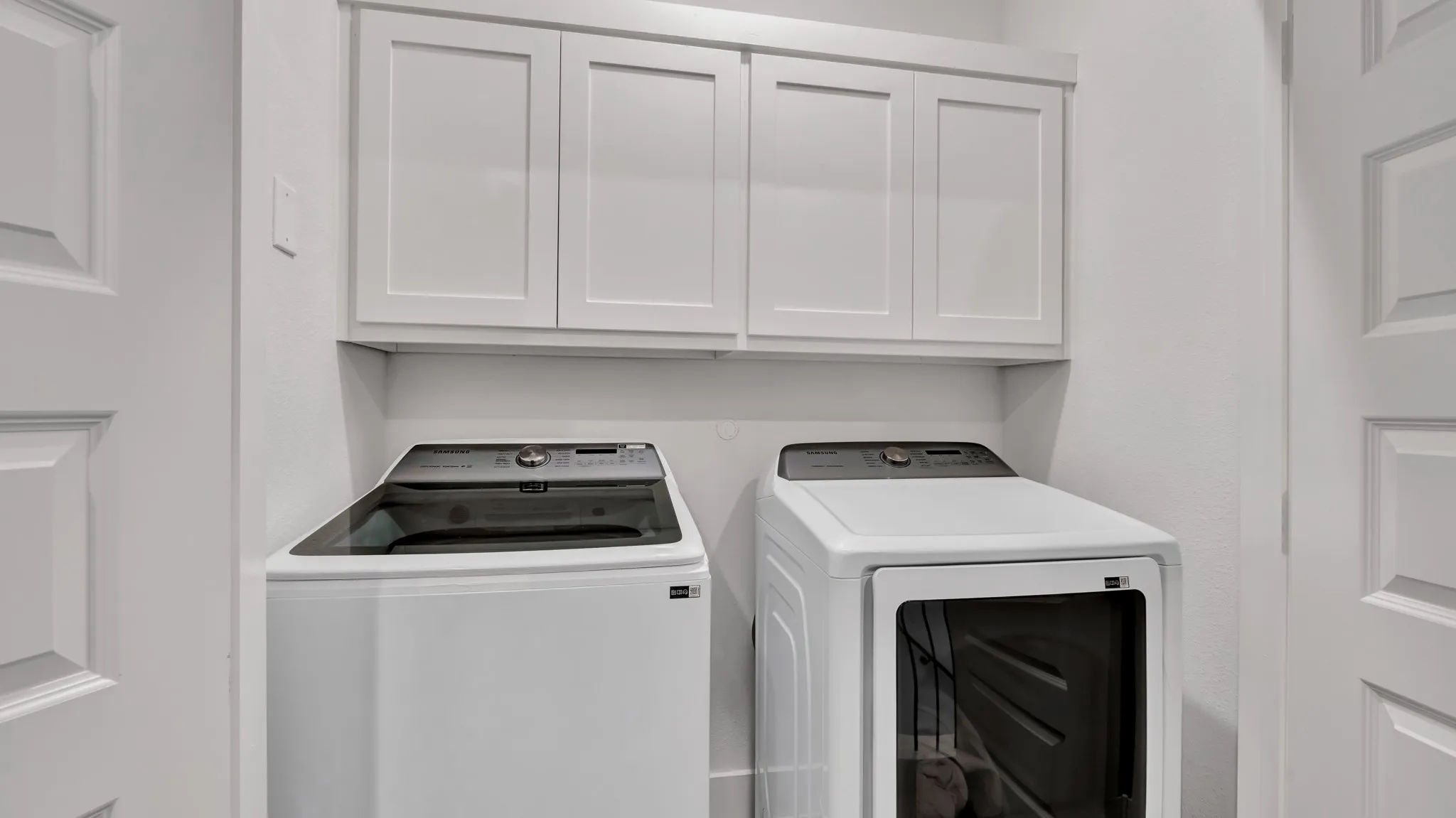 Laundry area featuring white shaker-style cabinetry, white walls, and paneled doors