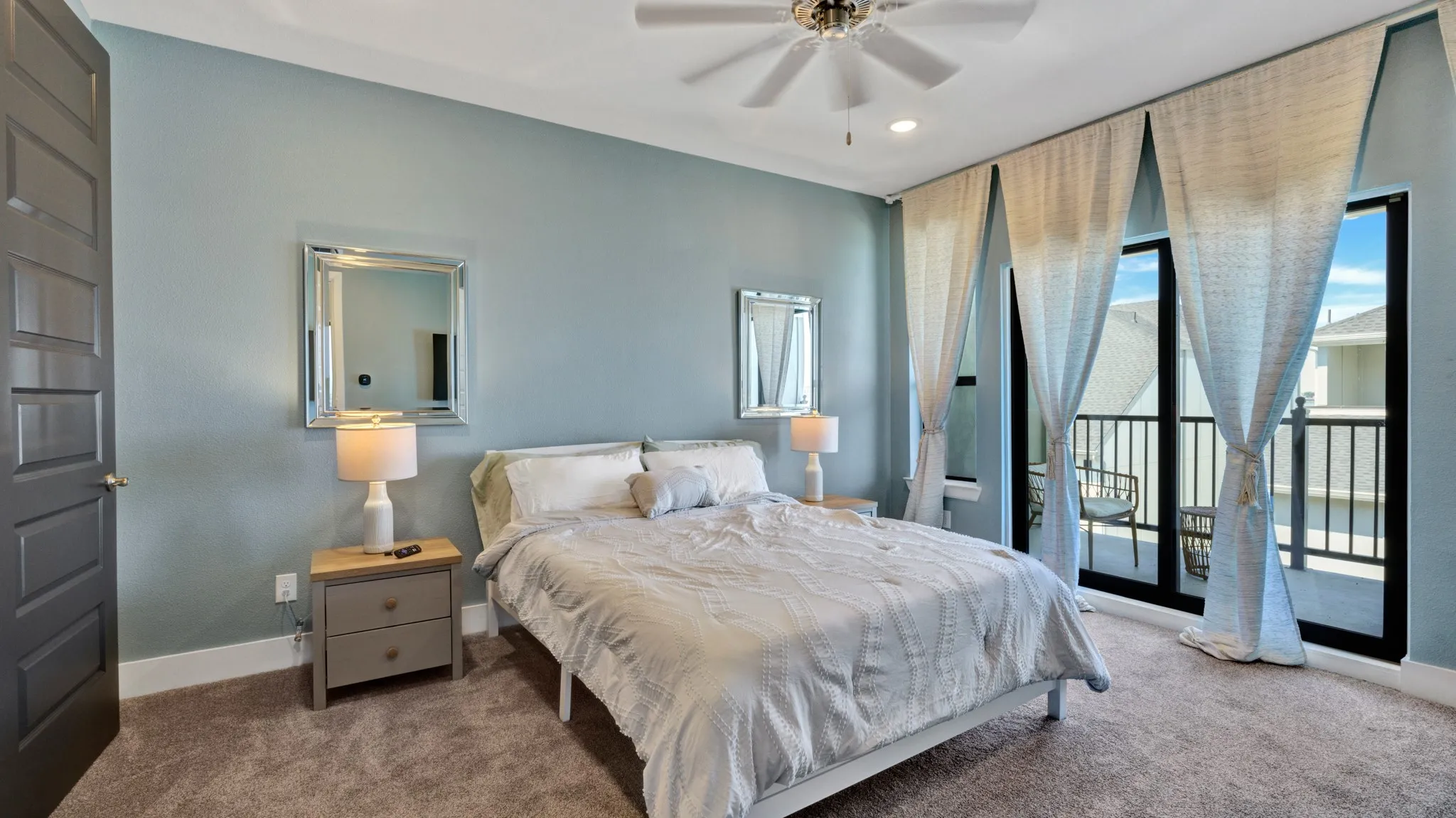 Third level, Master Bedroom featuring large glass doors leading to an outdoor balcony with lake view, black metal railings.