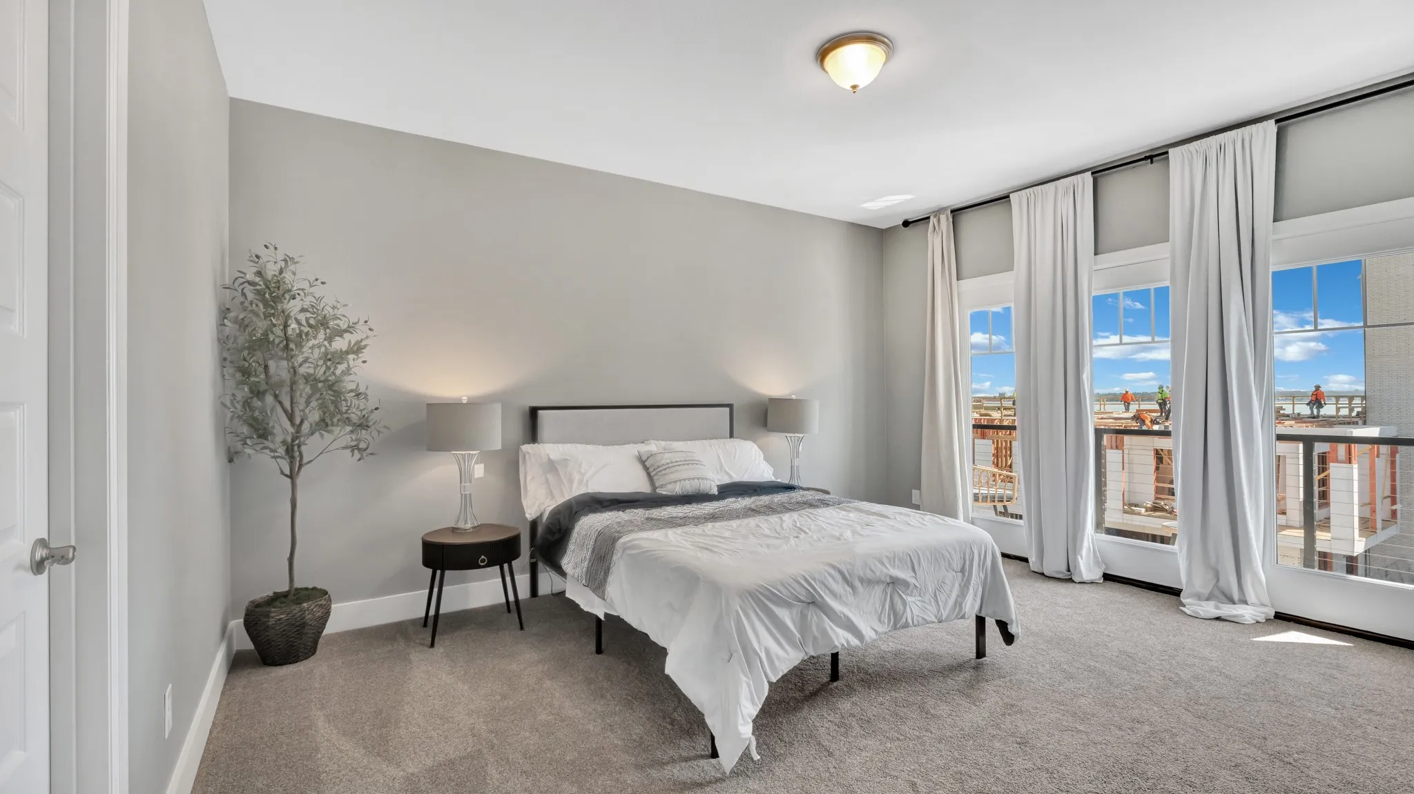 Third level, secondary bedroom, carpeted, featuring an ensuite, light gray color palette, multiple large windows with white trim, and a ceiling-mounted light fixture