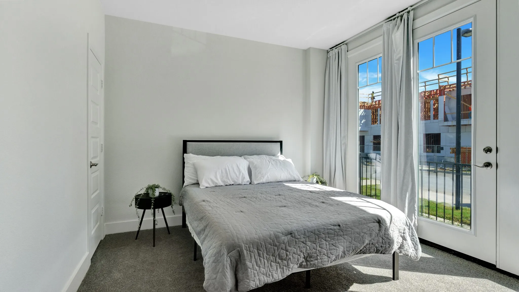 Ground level bedroom with recessed lighting, featuring a private door leading to the fornt yard, light gray walls, plush carpet flooring, and white trim.
