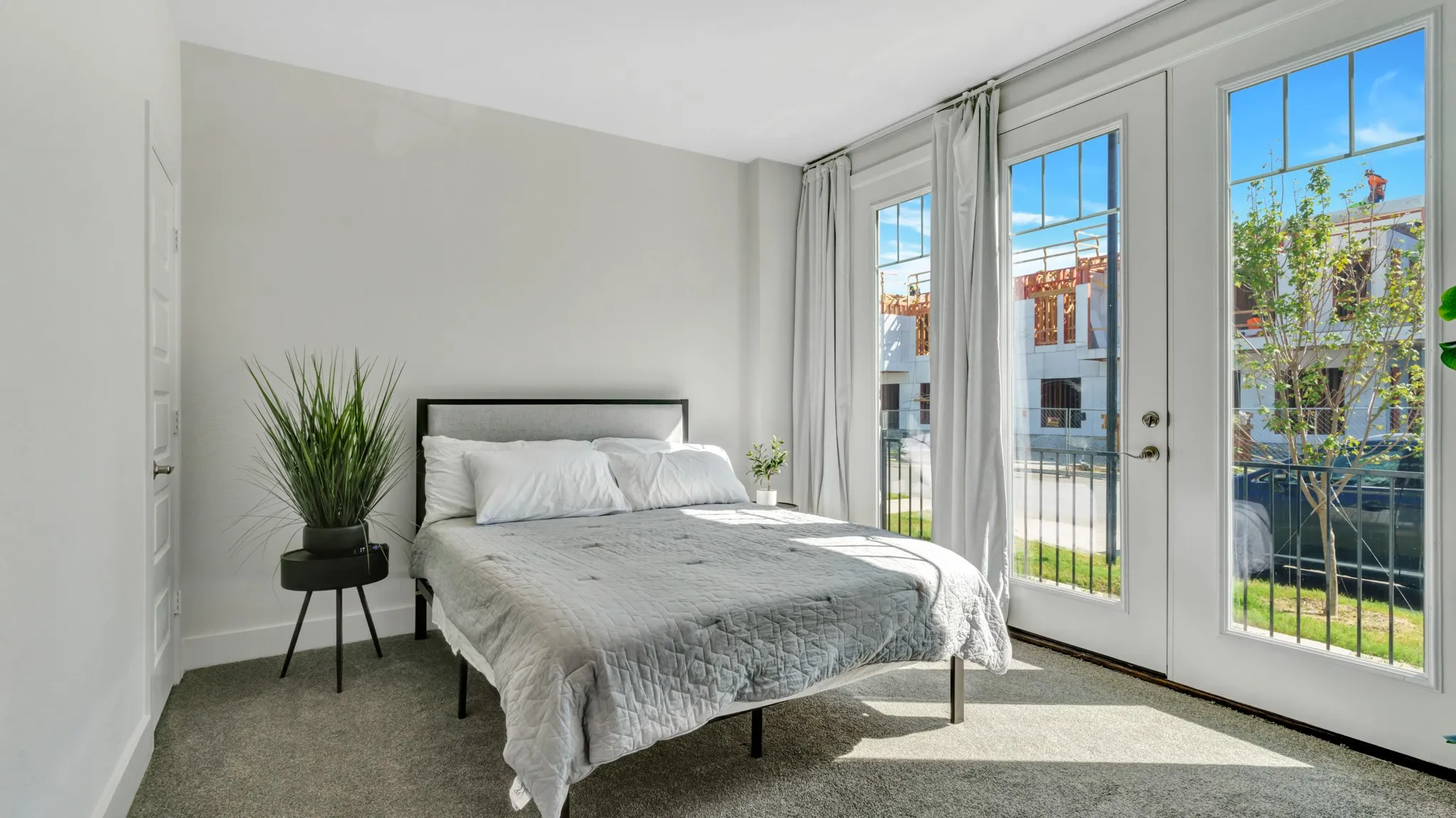 Ground level bedroom featuring light gray wall paint, gray carpet flooring, white trim, and a door that leads to the front yard.