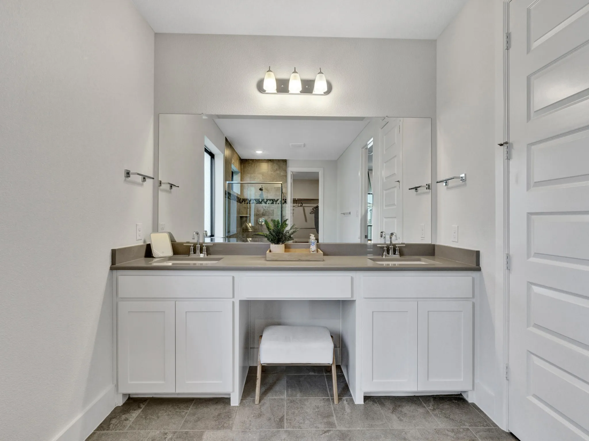 Mastyer bath, features a dual vanity with undermount sinks, grey countertop, and a full-width mirror