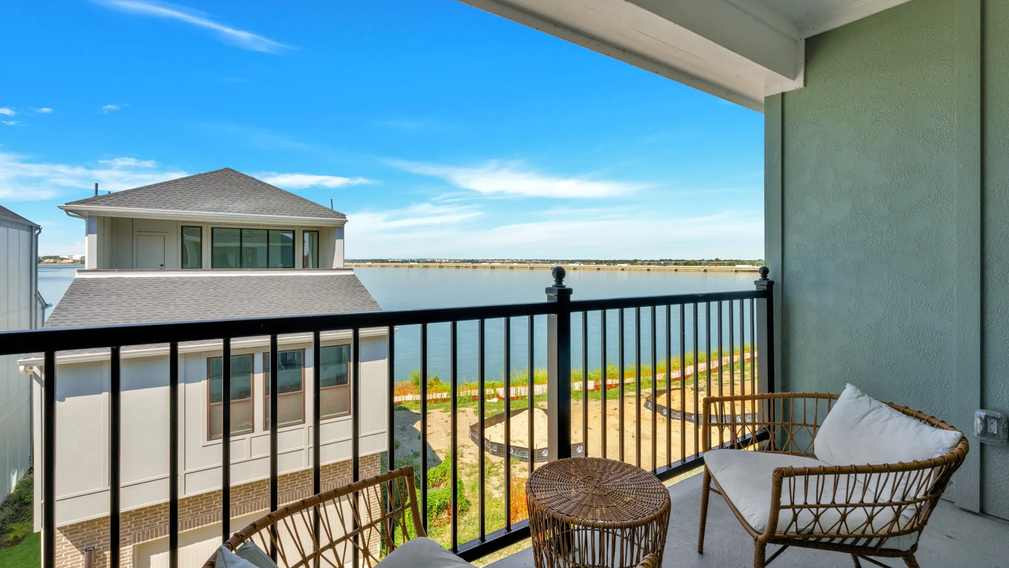Third level, Master Suite, private balcony with black iron railings and a textured exterior wall, offering waterfront exposure and distant horizon