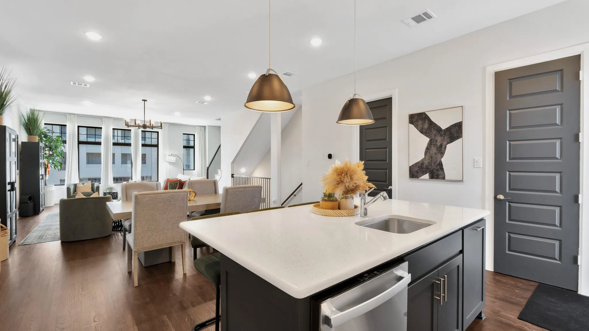 Kitchen island with white countertop and integrated sink, pendant lighting, looking back toward the dining , and living areas