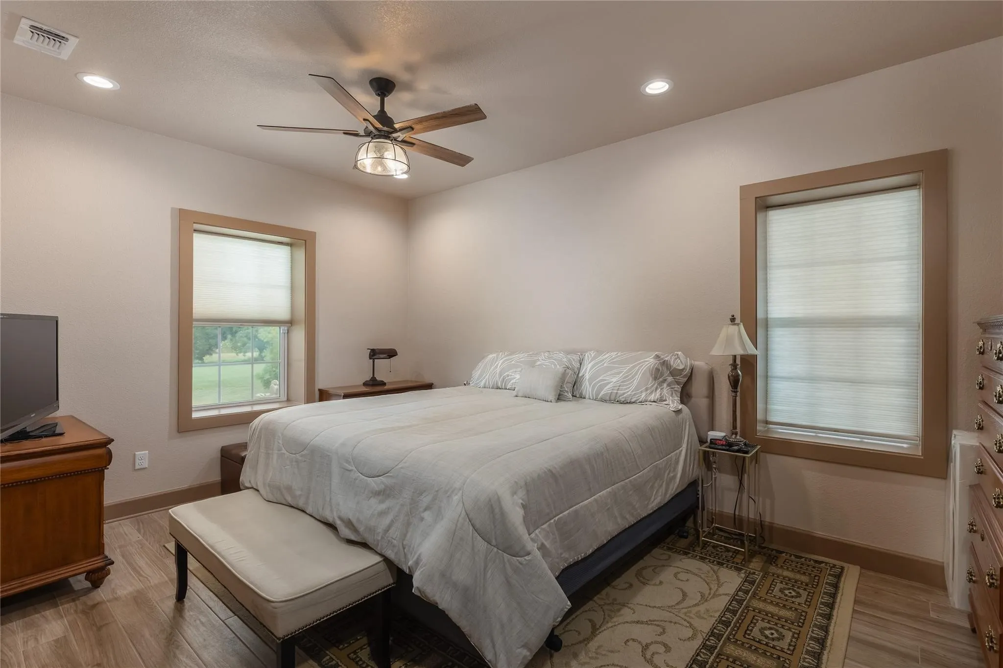 Room featuring wood-finish flooring, recessed lighting, and a ceiling fan with a bronze and glass fixture