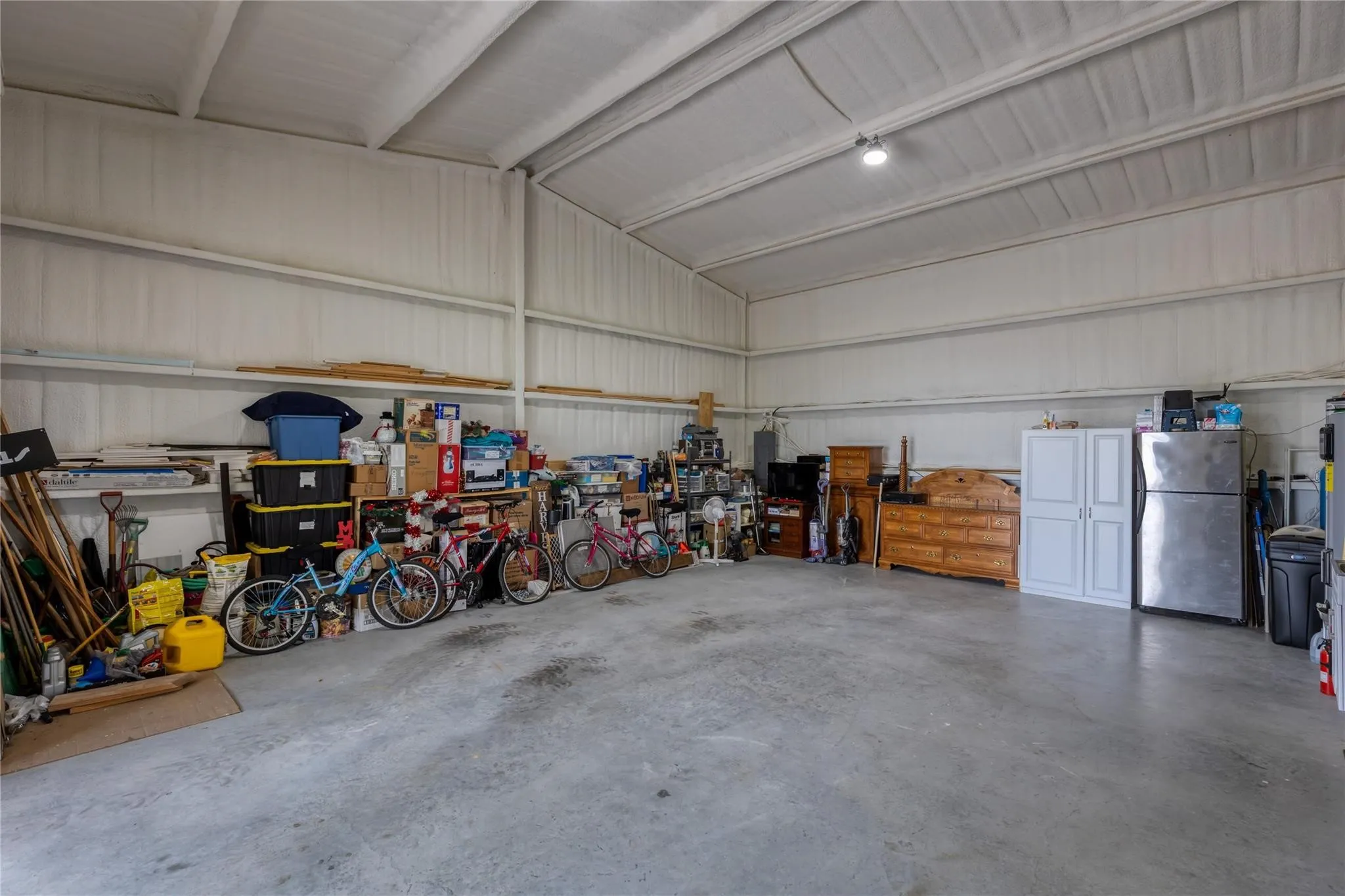 Expansive interior space featuring a concrete floor, high ceilings with exposed beams, and corrugated metal wall panels