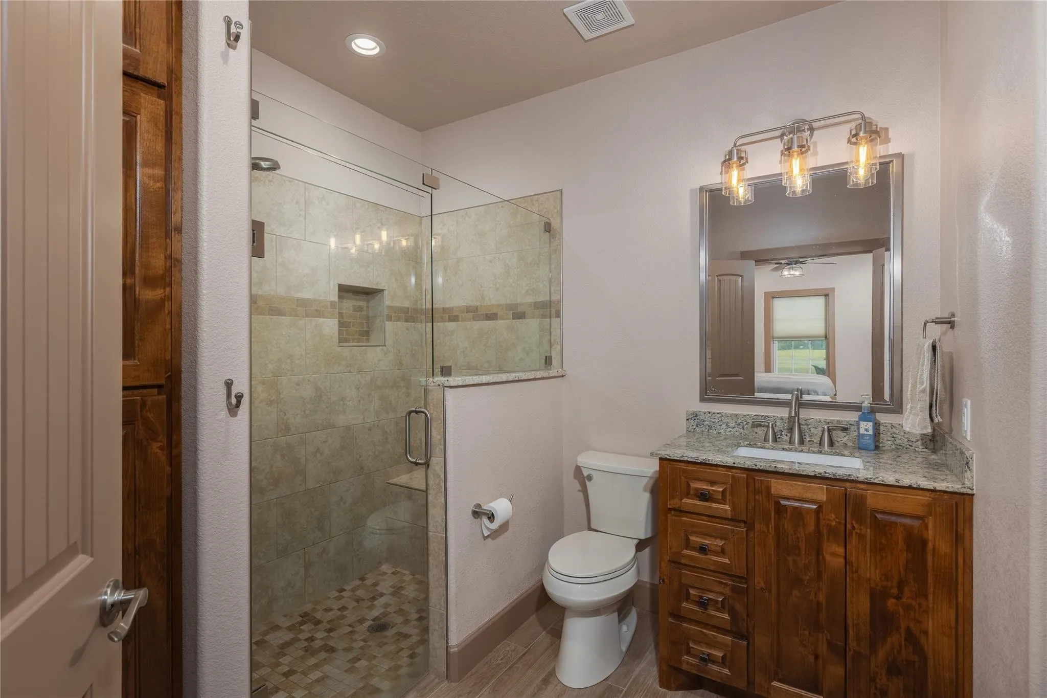 Bathroom featuring a glass-enclosed shower with pebble-style flooring and a tiled niche