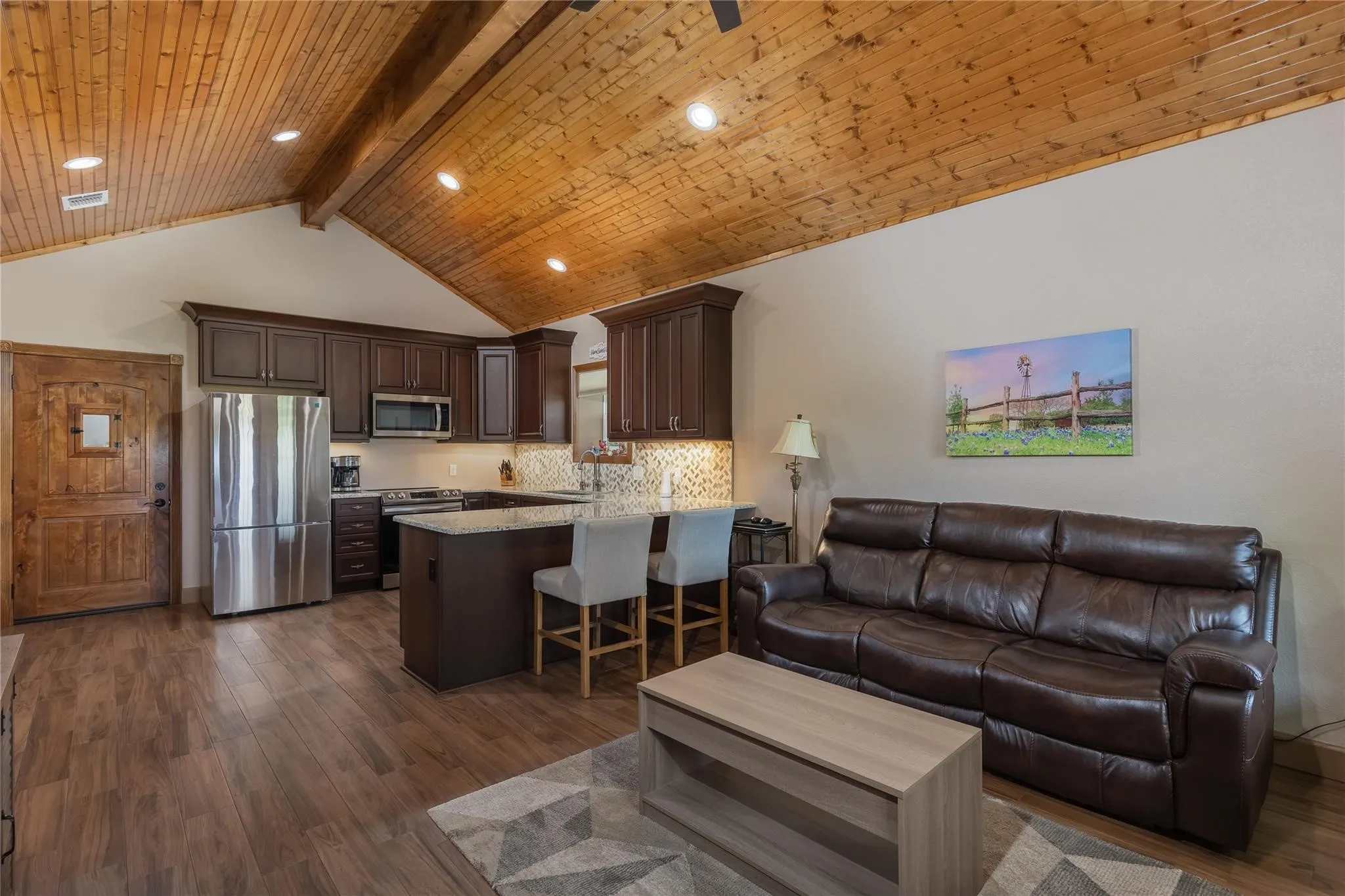 Vaulted wood-paneled ceiling with exposed beam and recessed lighting