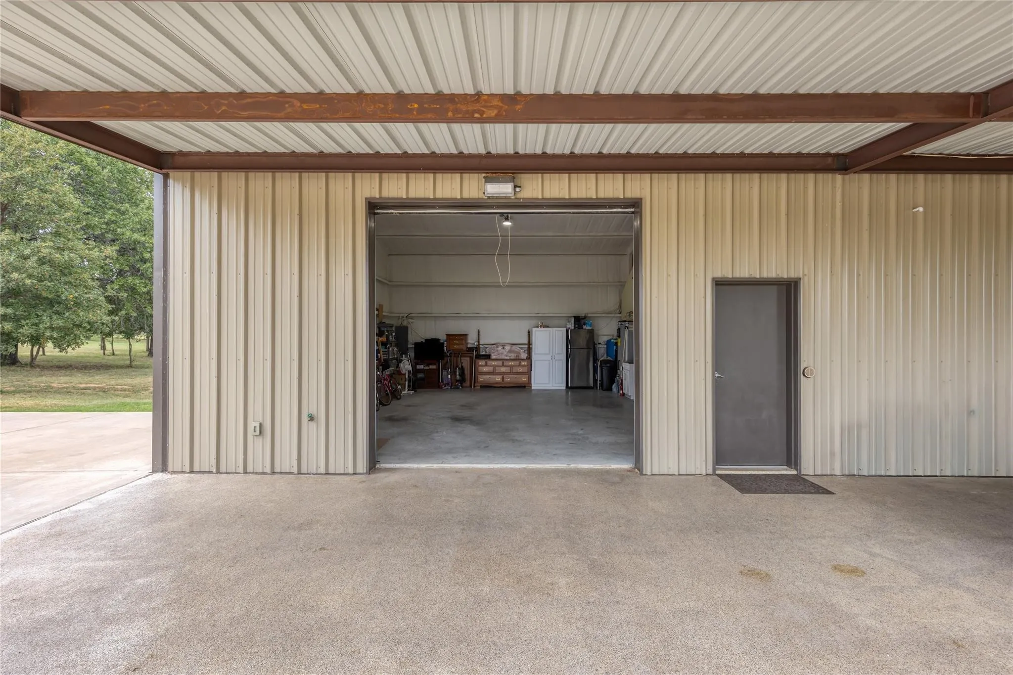 Metal-sided outbuilding with a large open bay, a separate entry door, and a concrete floor