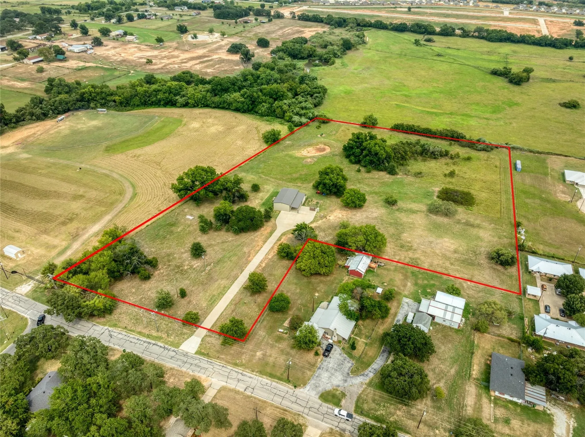 Expansive acreage featuring a main residence, a secondary structure, mature trees, and a paved driveway