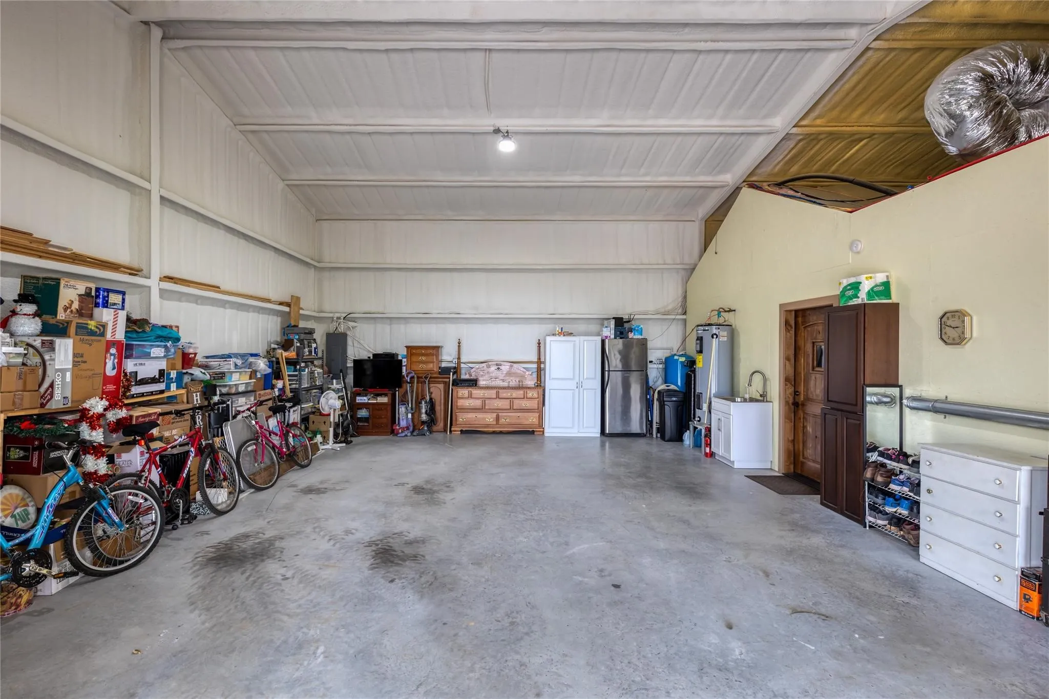Spacious utility building featuring a concrete floor, high ceilings, and corrugated metal walls