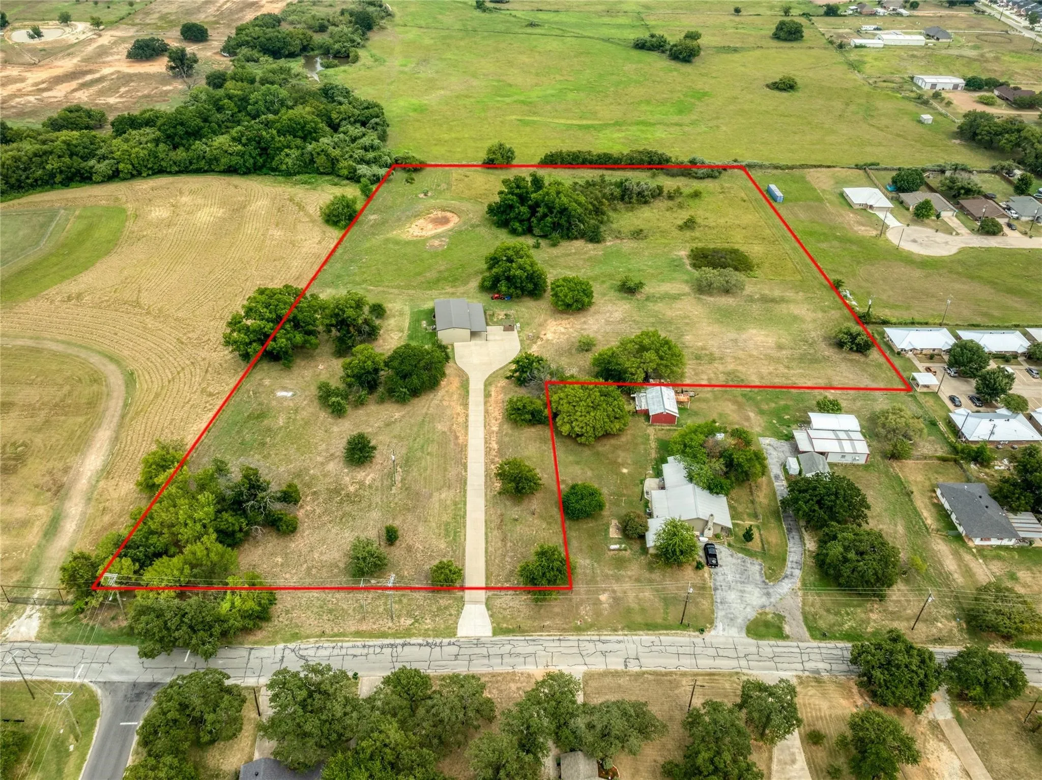 Expansive rural property featuring a long driveway, a detached garage, and a secondary structure