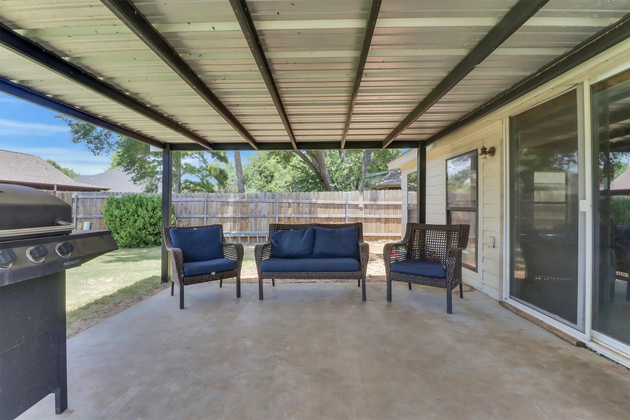 Expansive covered patio featuring a concrete surface, metal roofing, and a privacy fence