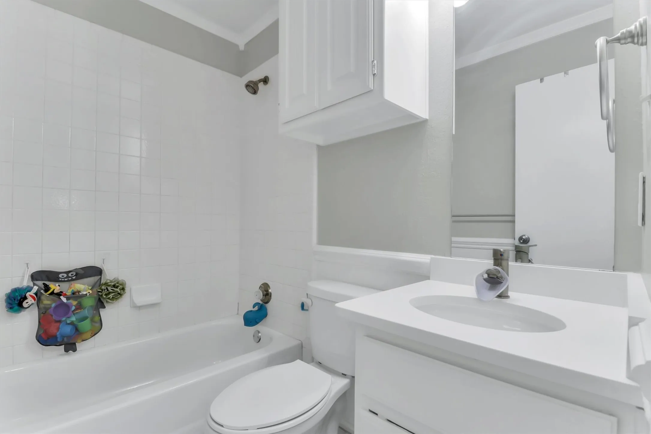 Bathroom featuring a white vanity with integrated sink, chrome faucet, and a large wall-mounted mirror