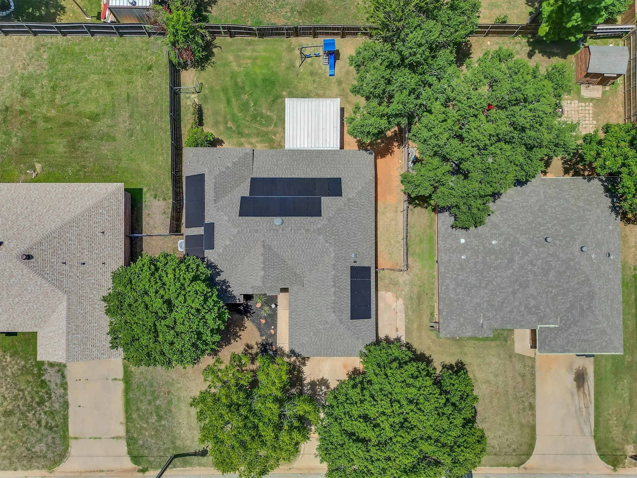 Aerial perspective showcasing the property with a shingle roof and multiple solar panels