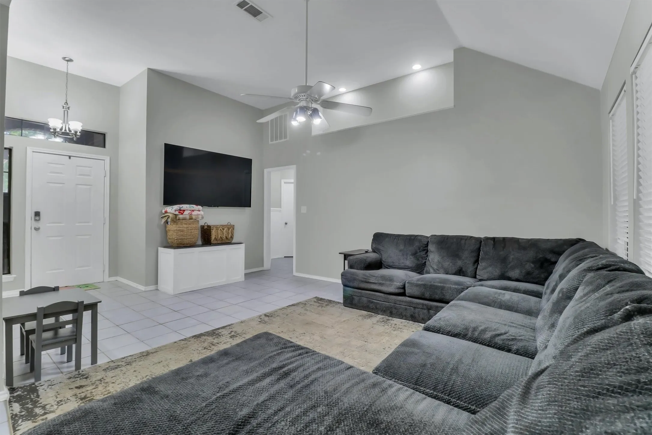 Spacious living area featuring vaulted ceilings, recessed lighting, and tile flooring