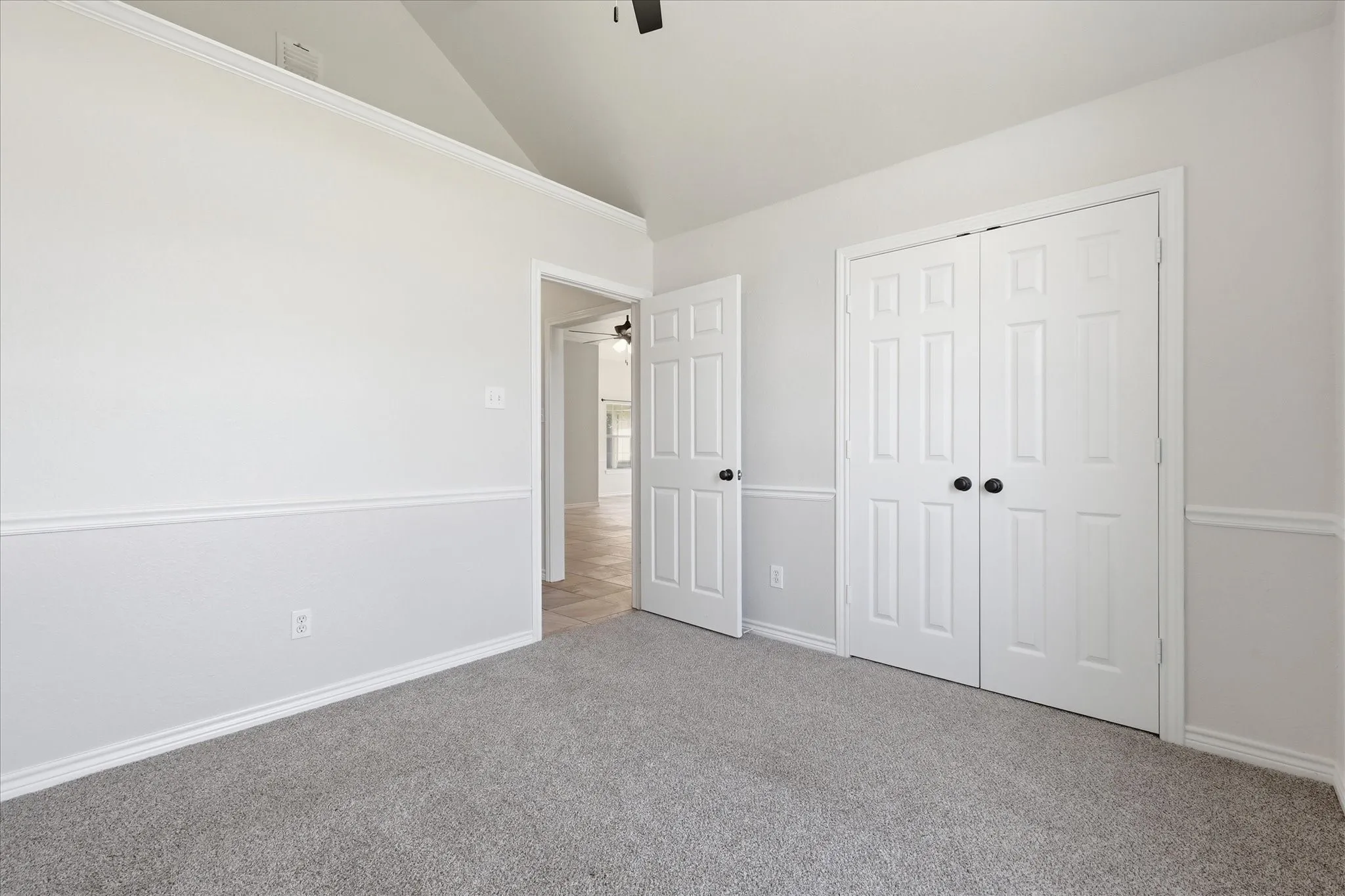 Carpeted room with vaulted ceiling and crown molding