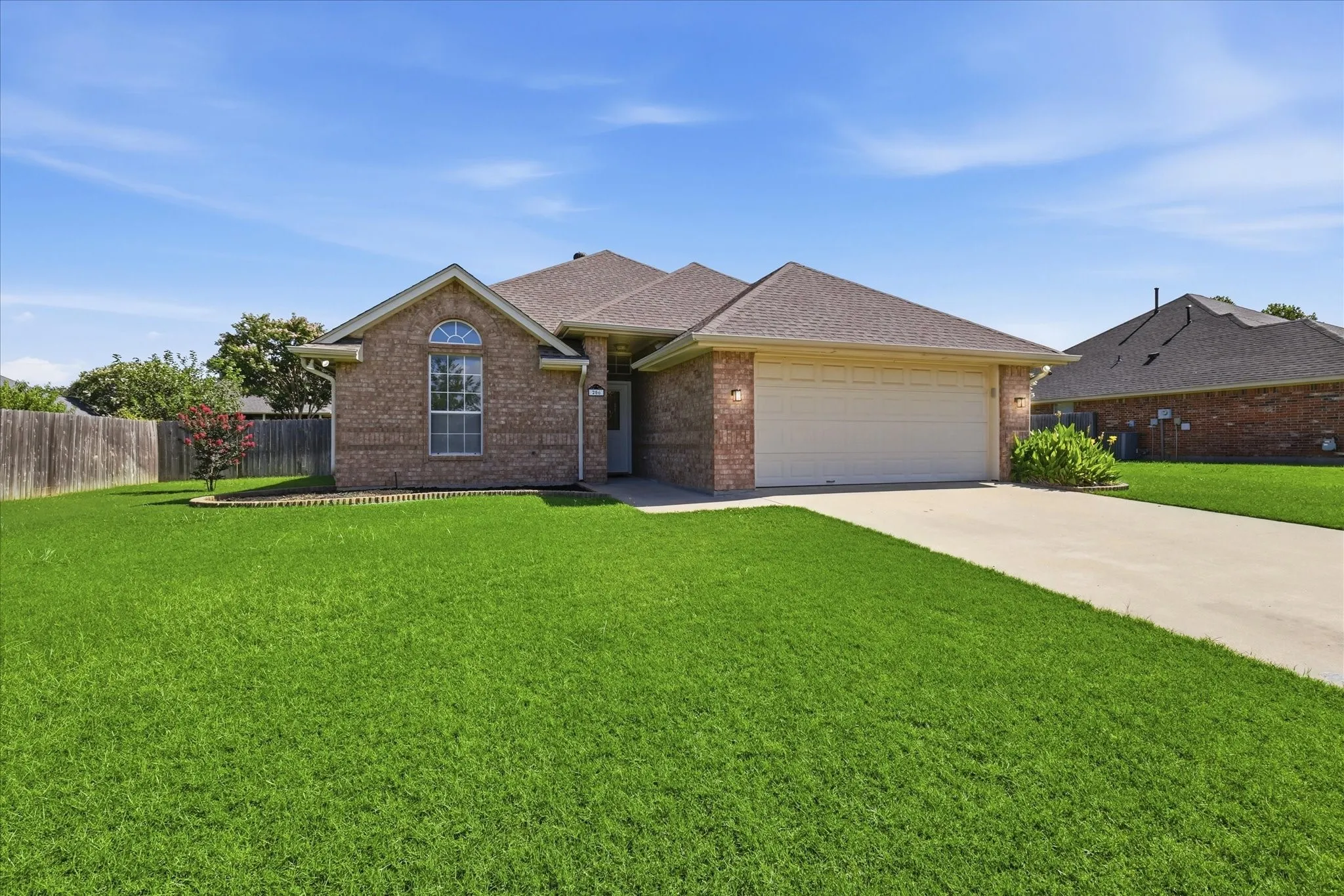 Brick exterior featuring a two-car garage and a concrete driveway